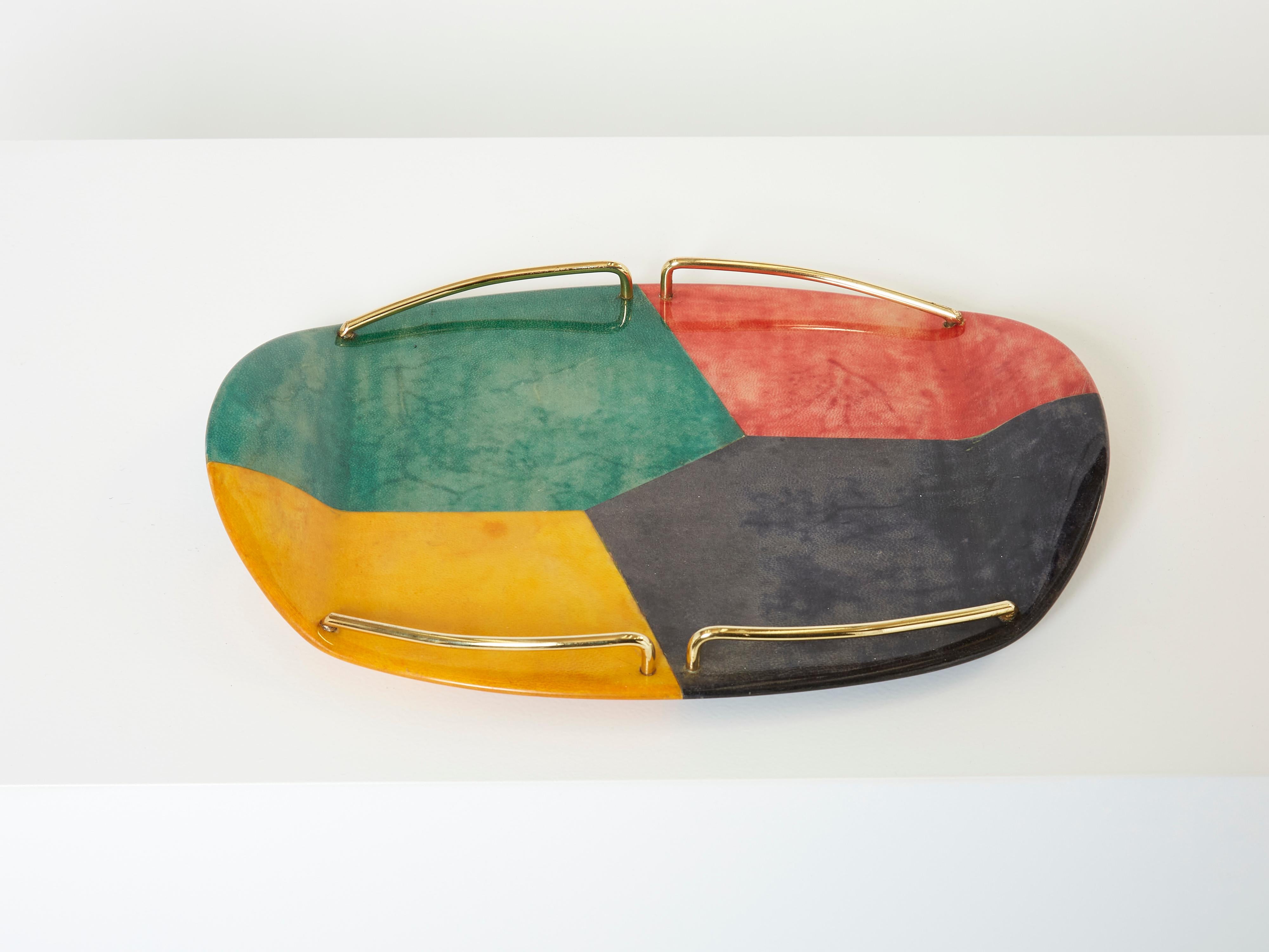 This is a beautiful barware serving tray designed by Aldo Tura for Macabo Cusano Milanino in Milan in the early 1960s. Rounded shape with a brass gallery and varnished goatskin parchment patchwork, in rich shades of yellow, red, green and black,