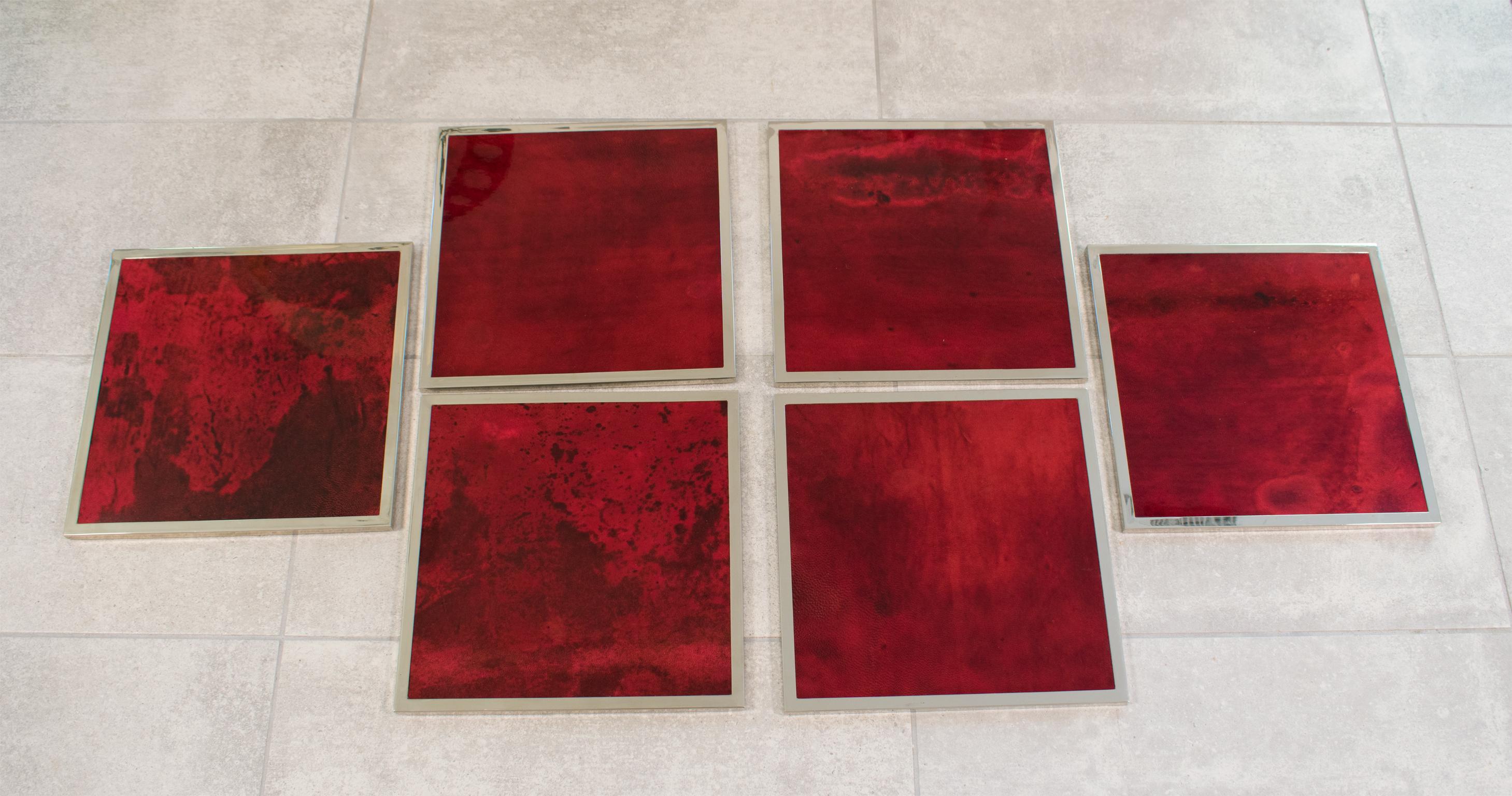 Italian designer Aldo Tura, Milano, designed this lacquered goatskin and chromed metal placemat or plate charger set in the 1970s. The pieces boast a beautiful square wooden base design covered with high gloss oxblood-colored goatskin parchment