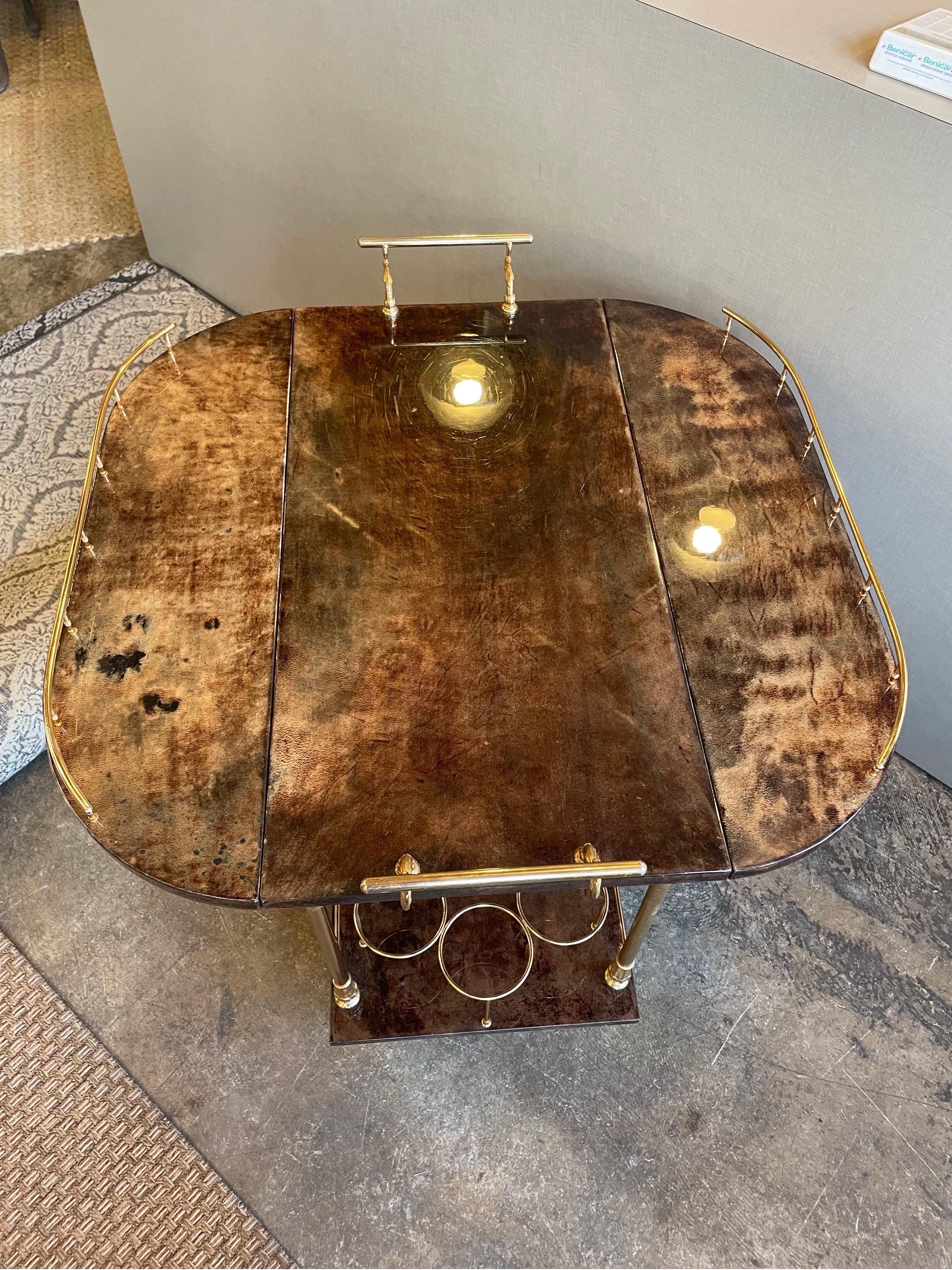 This is a wonderful goatskin and brass bar cart by Aldo Tura and made in Milano Italy in 1960s 
Great vintage condition and wheels have some wear to them 
It also has two drop leaf sides 