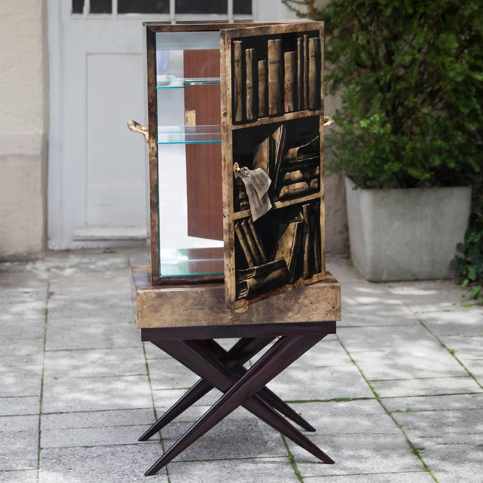 Wonderful sculptural bar cabinet made by Aldo Tura in the 1960s. The Trompe l'oeil painted goatskin surface seems in a three-dimensional book shelf based on a tanned pearwood x base. Mirrored inside and fitted with an interior light.
Dimensions: 122