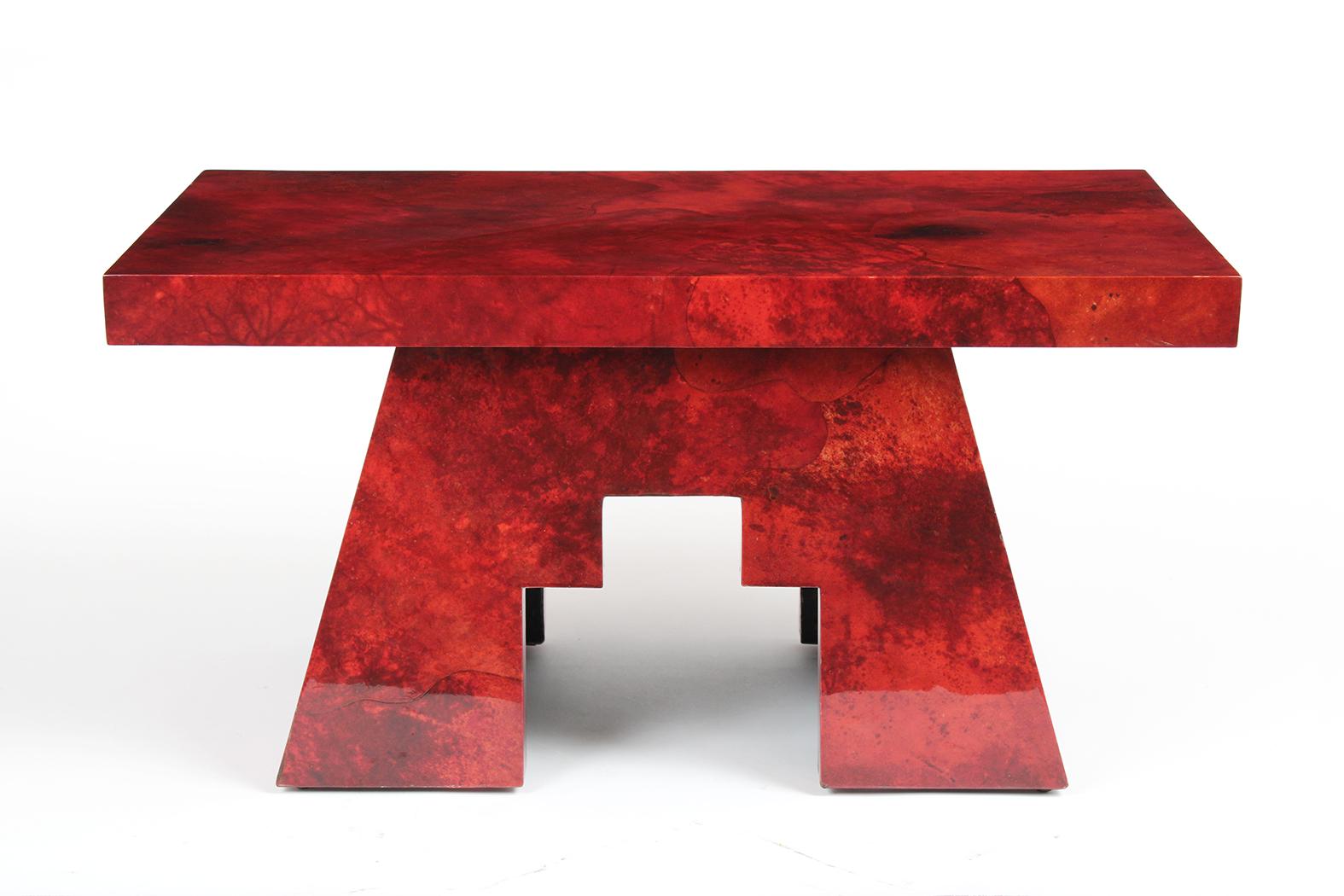 This 1980's Red Goatskin End Table by Aldo Tura is in great condition and has a unique design. The side table has a rectangular top, asymmetrical leg design, and is covered in a deep red-dyed color goatskin with a lacquered finish. This Vintage Side