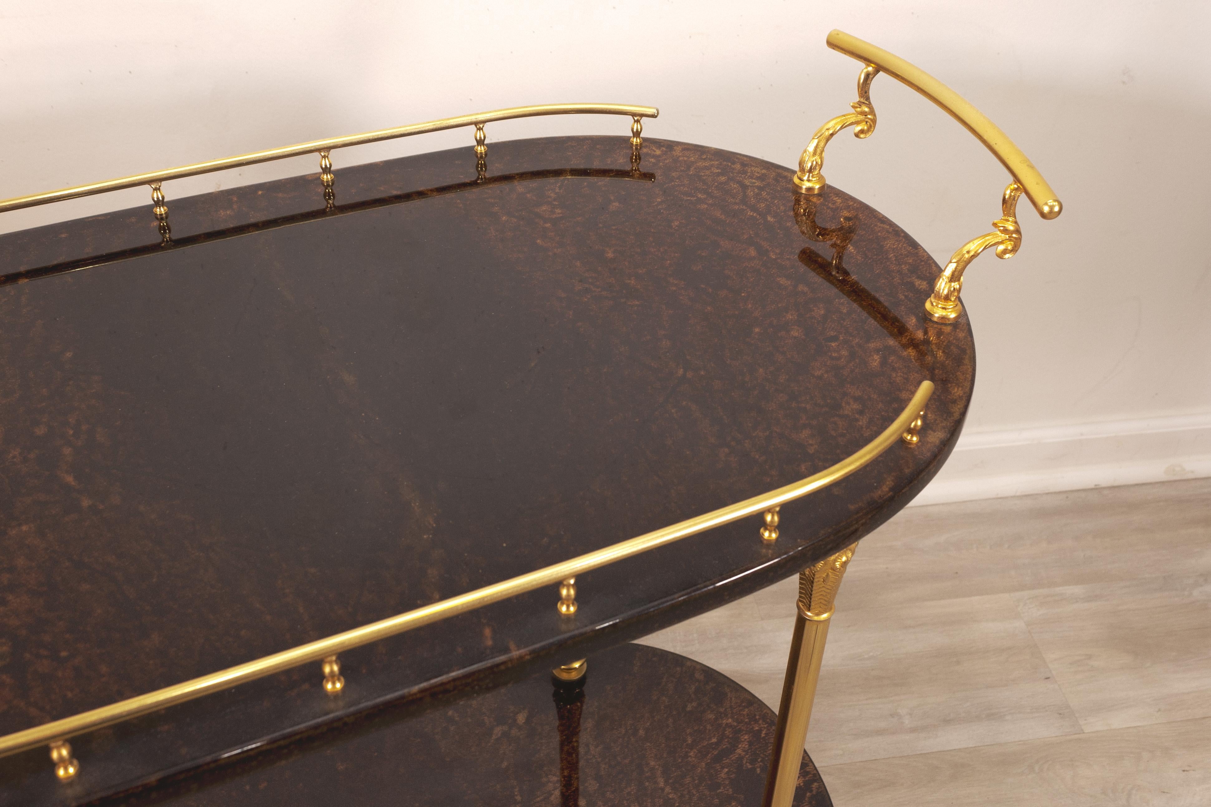An Aldo Tura 1960s mid century modern Italian bar cart. This piece features a very chic set of materials in brass and goatskin. This piece has two tiers, each tier having a goatskin parchment table top with a lacquered finish. The frame is made with