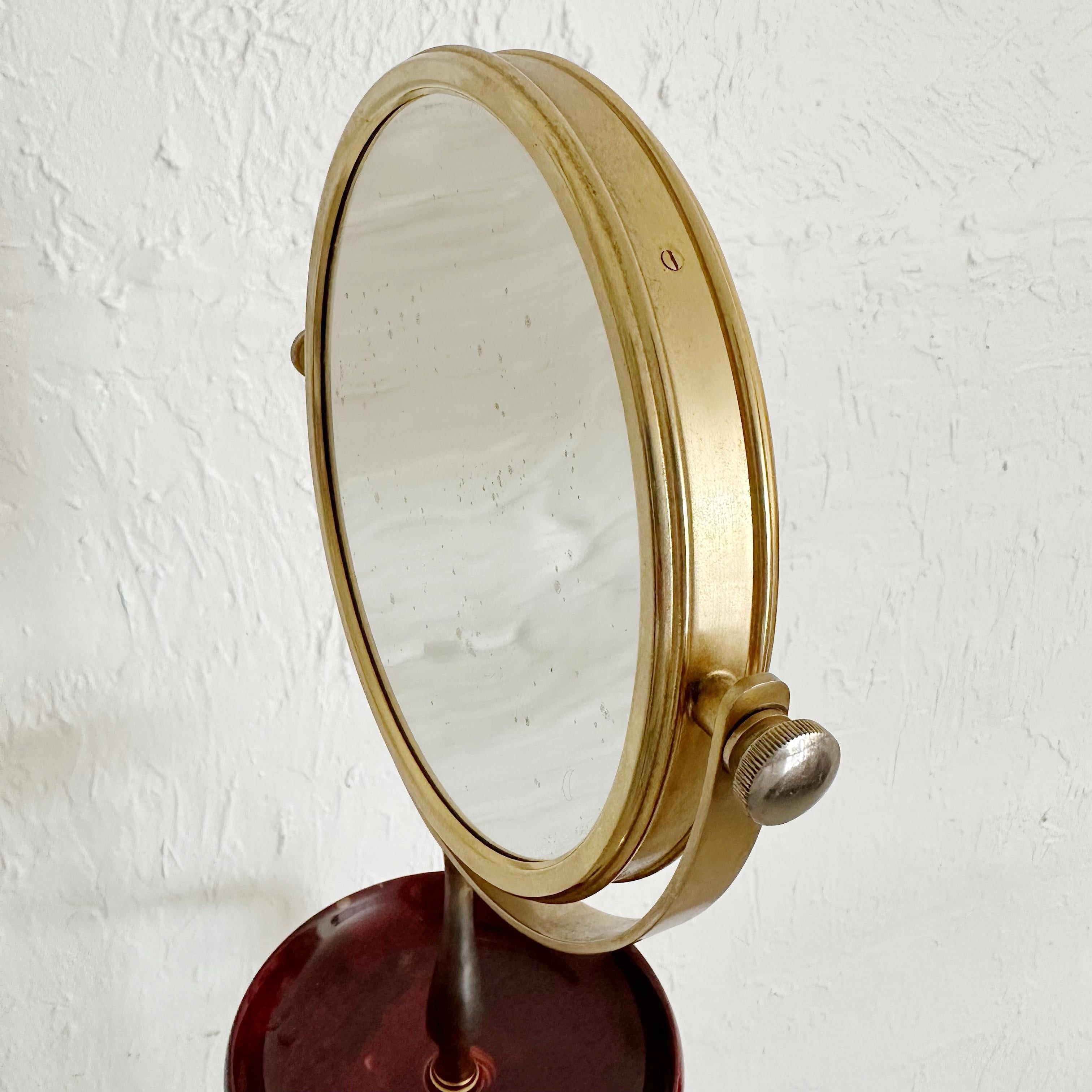 Aldo Tura red goatskin and gold finished brass valet stand with mirror. The mirror is reversible with magnifying on one side and standard mirror on other side. Spot to hang pants and jacket / shirts and a small catchall for cufflinks or other