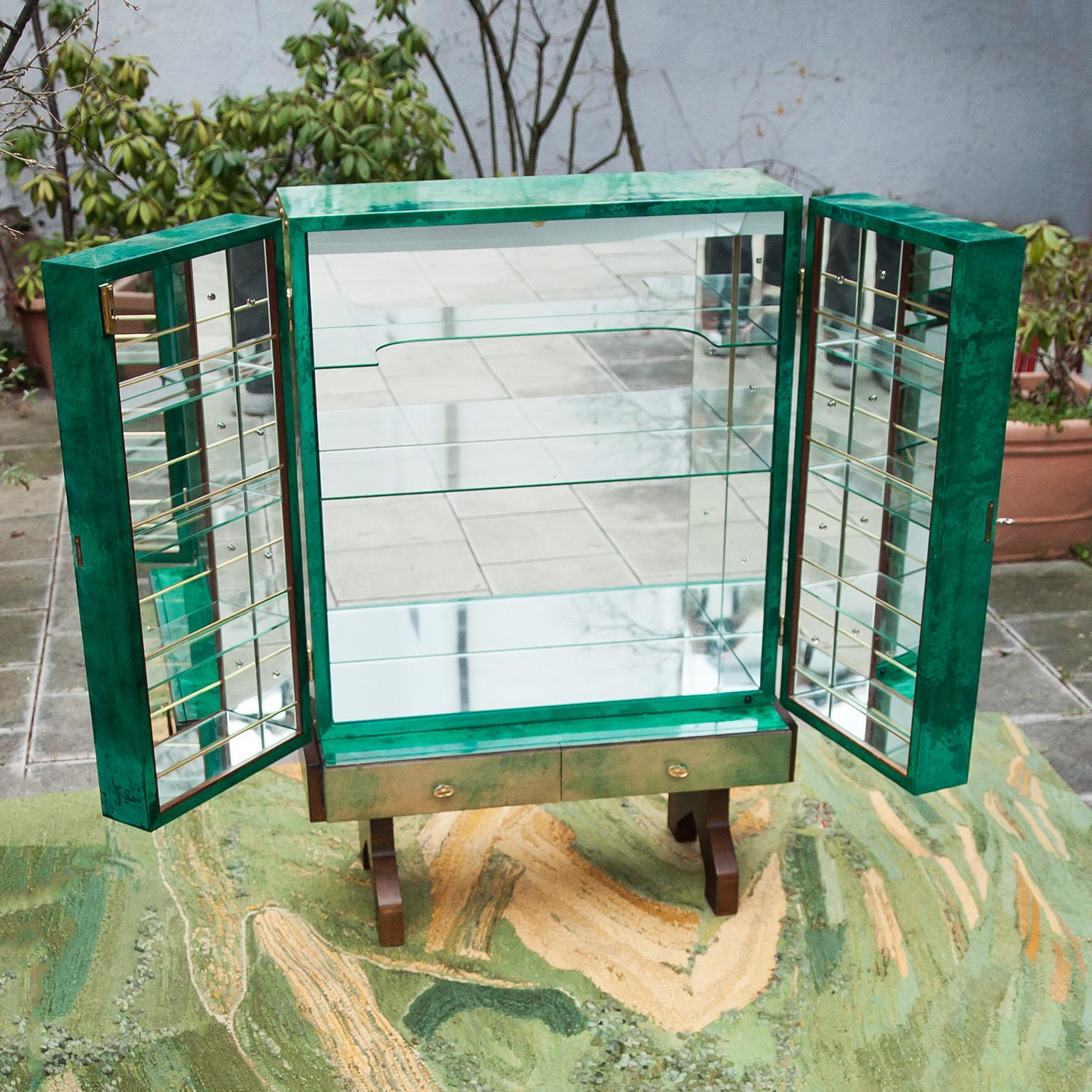 Barschrank aus grünem Ziegenleder von Aldo Tura, Italien, um 1960. Dieser schöne zweitürige Schrank ist innen beleuchtet und verspiegelt, mit drei Glasböden und Messingapplikationen, montiert auf einem Sockel aus gebeizter Eiche. Ausgezeichneter