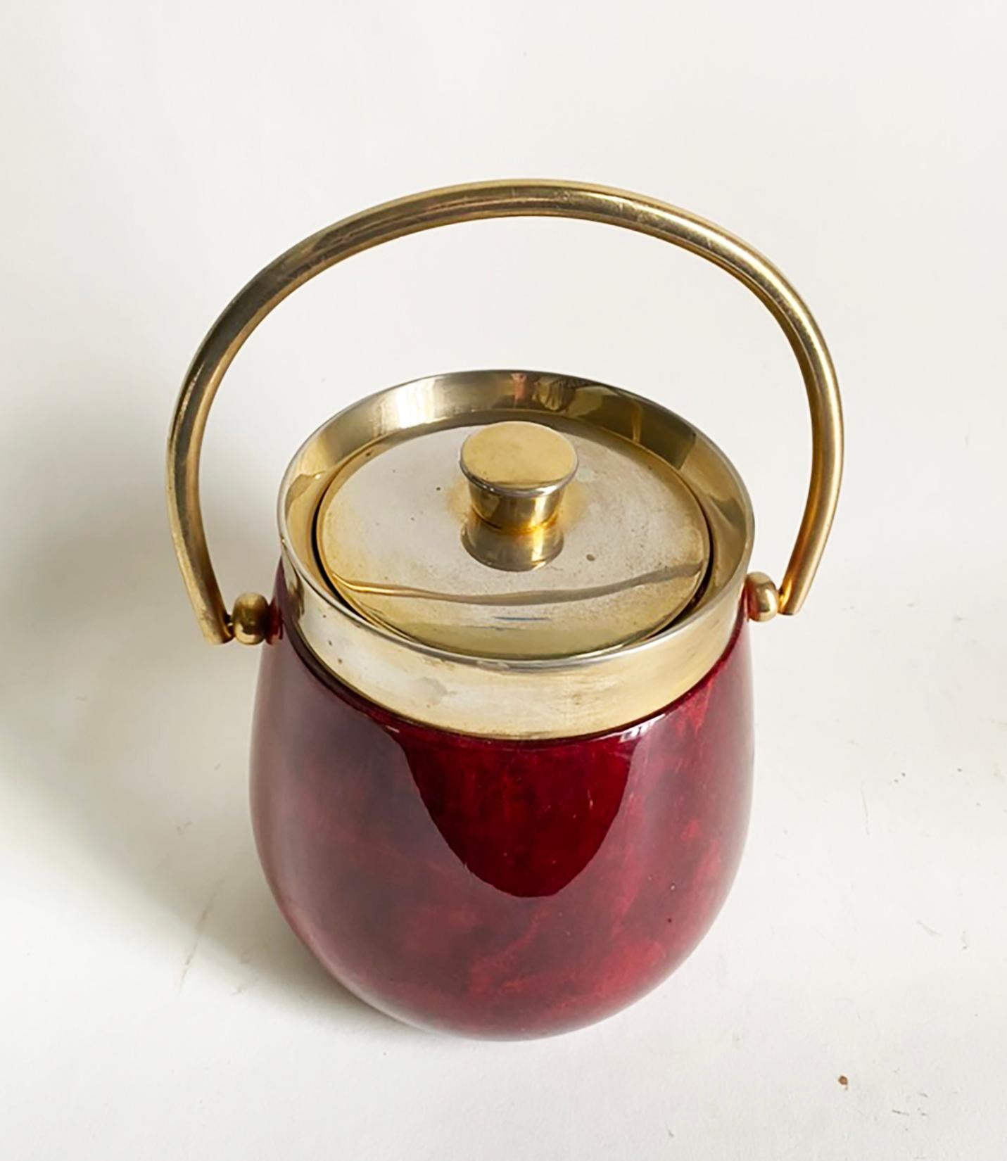 Voici un joli seau à glace du designer italien Aldo Tura. Cet exemplaire est en parchemin rouge richement laqué, avec une garniture, une poignée et un couvercle en laiton. Cette pièce est en bon état et présente bien. La peau de chèvre présente une