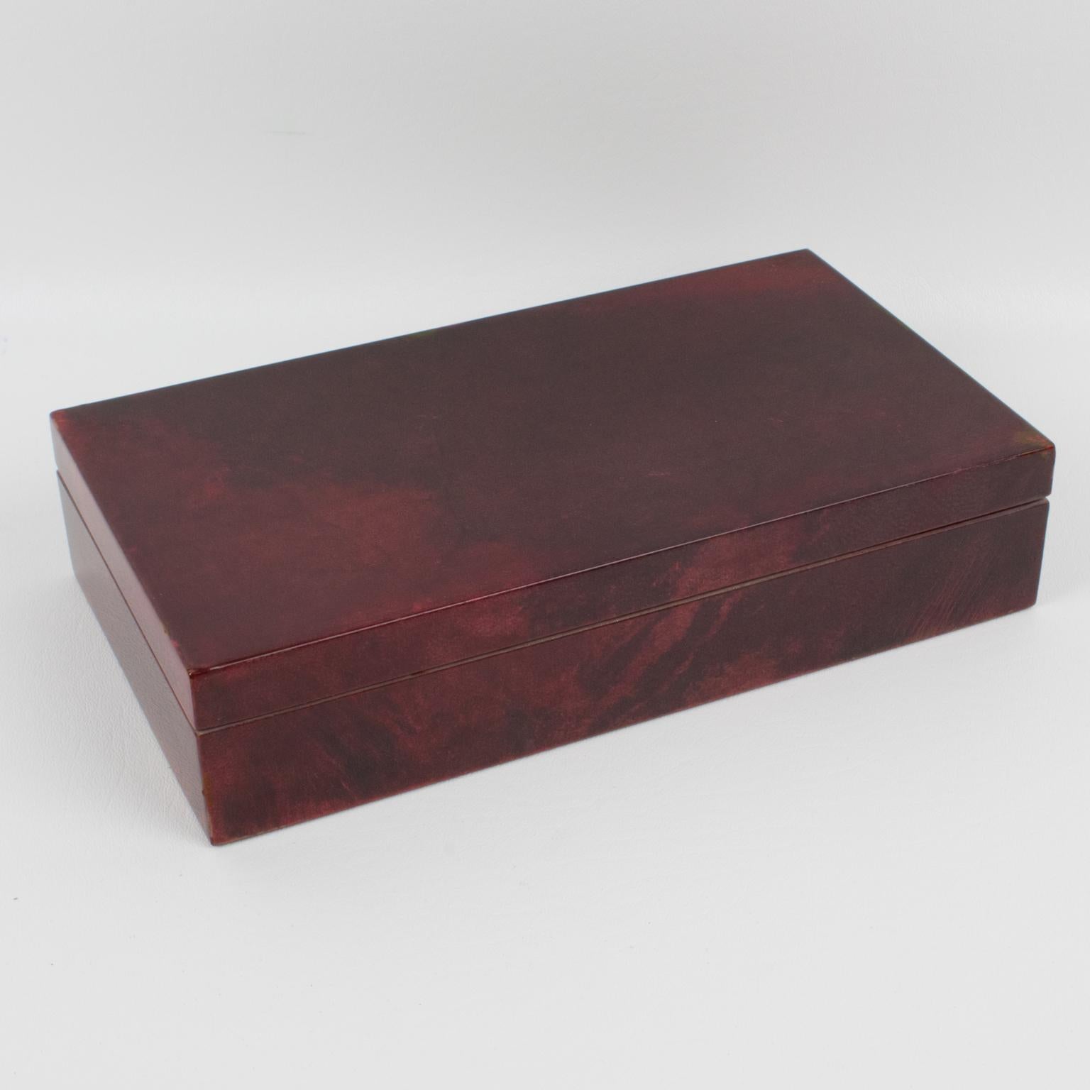 Refined lacquered goatskin decorative lidded box by Italian designer Aldo Tura, Milano. A 1970s rectangular wooden box with lacquered oxblood colored goatskin parchment veneer. Interior in high gloss lacquered wood. The original Aldo Tura label
