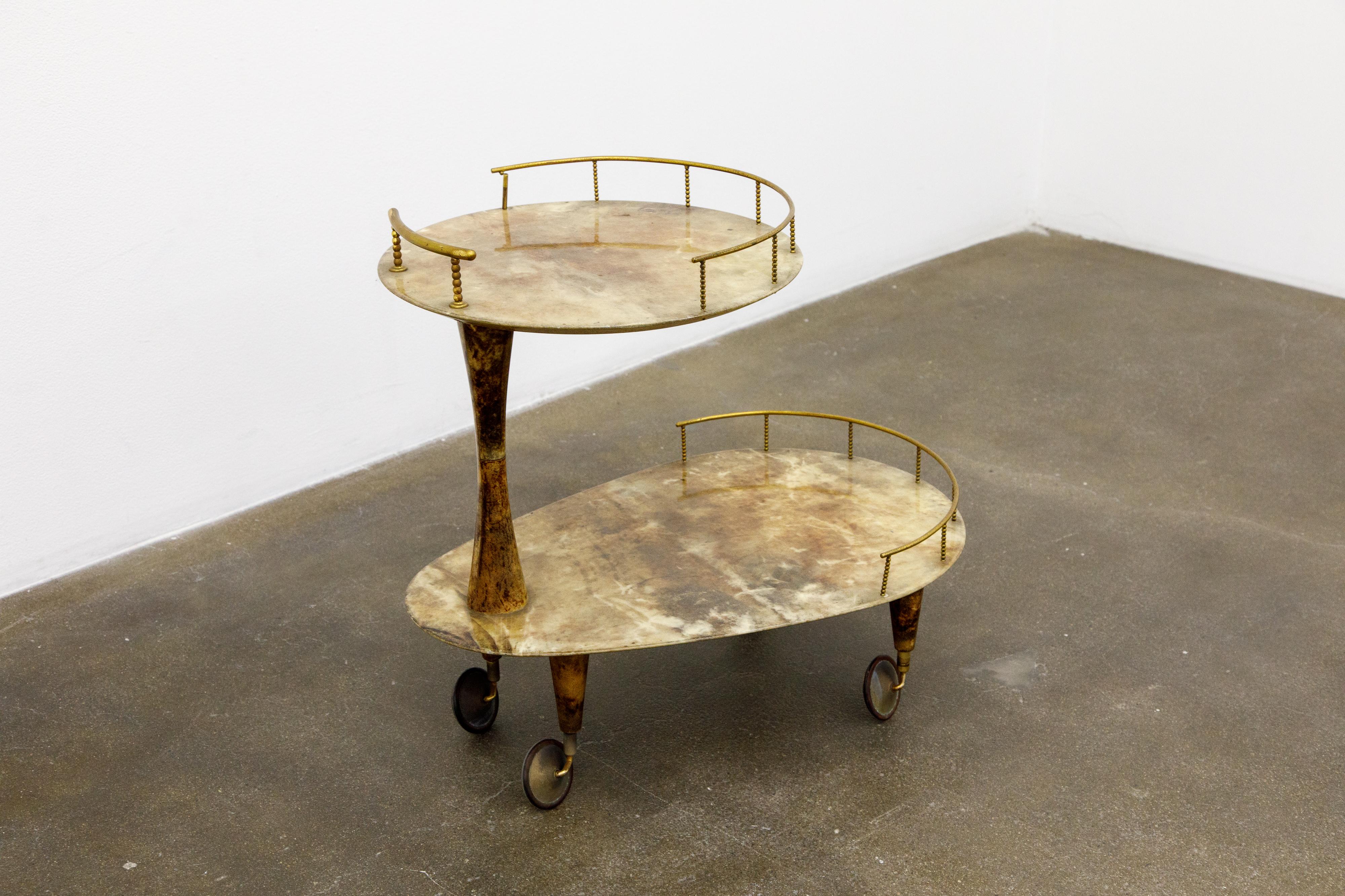 Beautiful 1950s bar cart by Italian artist-craftsman Aldo Tura featuring the designers distinct use of brass and marbleized brown lacquered goatskin that Tura was well-known for. The quality of Aldo Tura's craftsmanship can be attributed to the fact