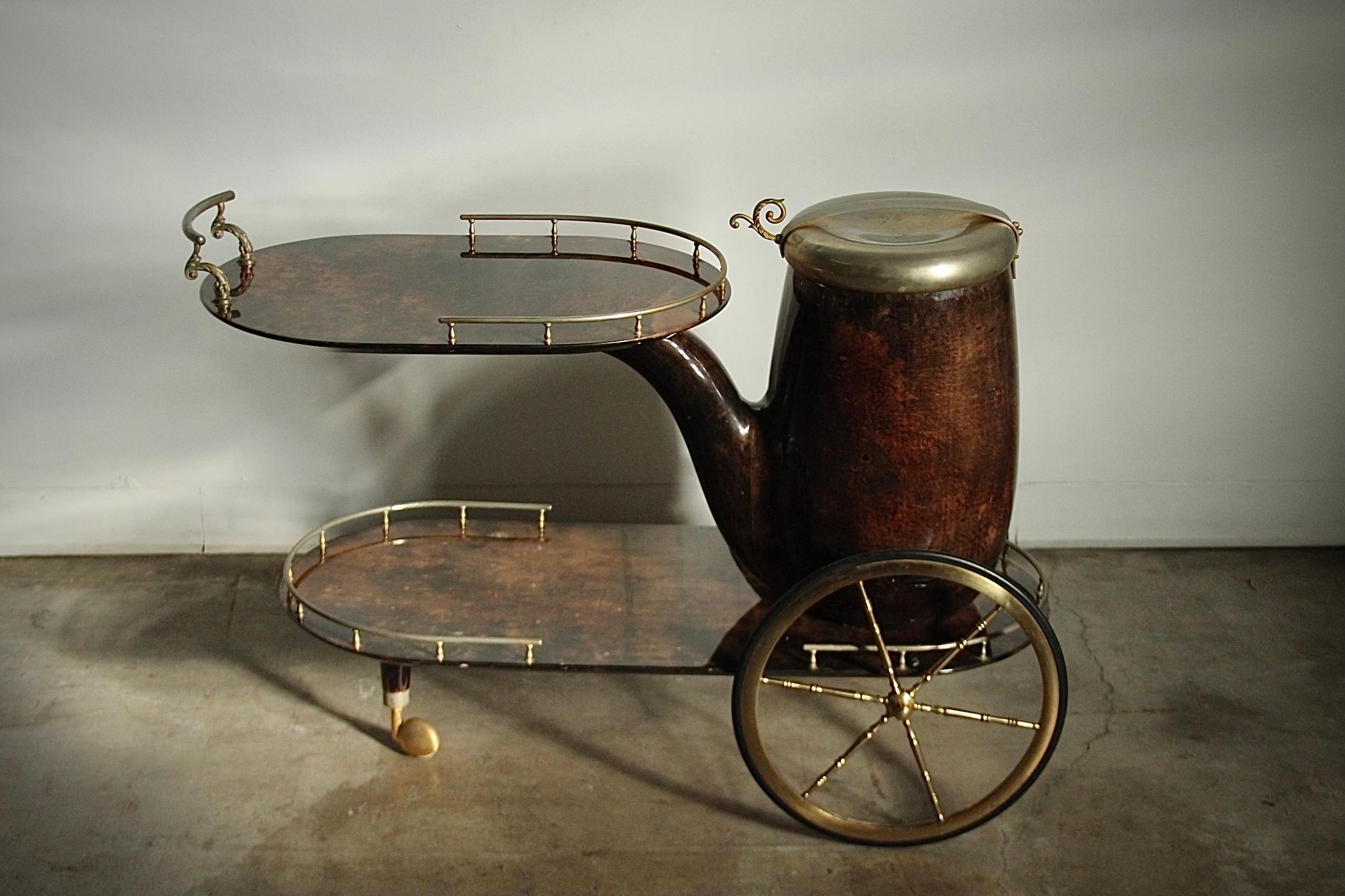 A fantastic pipe form bar cart by Aldo Tura in dyed and lacquered goatskin and brass detailing, circa 1960s. The large brass lidded pipe head serves as bottle storage or a wine/champagne cooler, with ample room for ~5 bottles. This uncommon, 1-owner