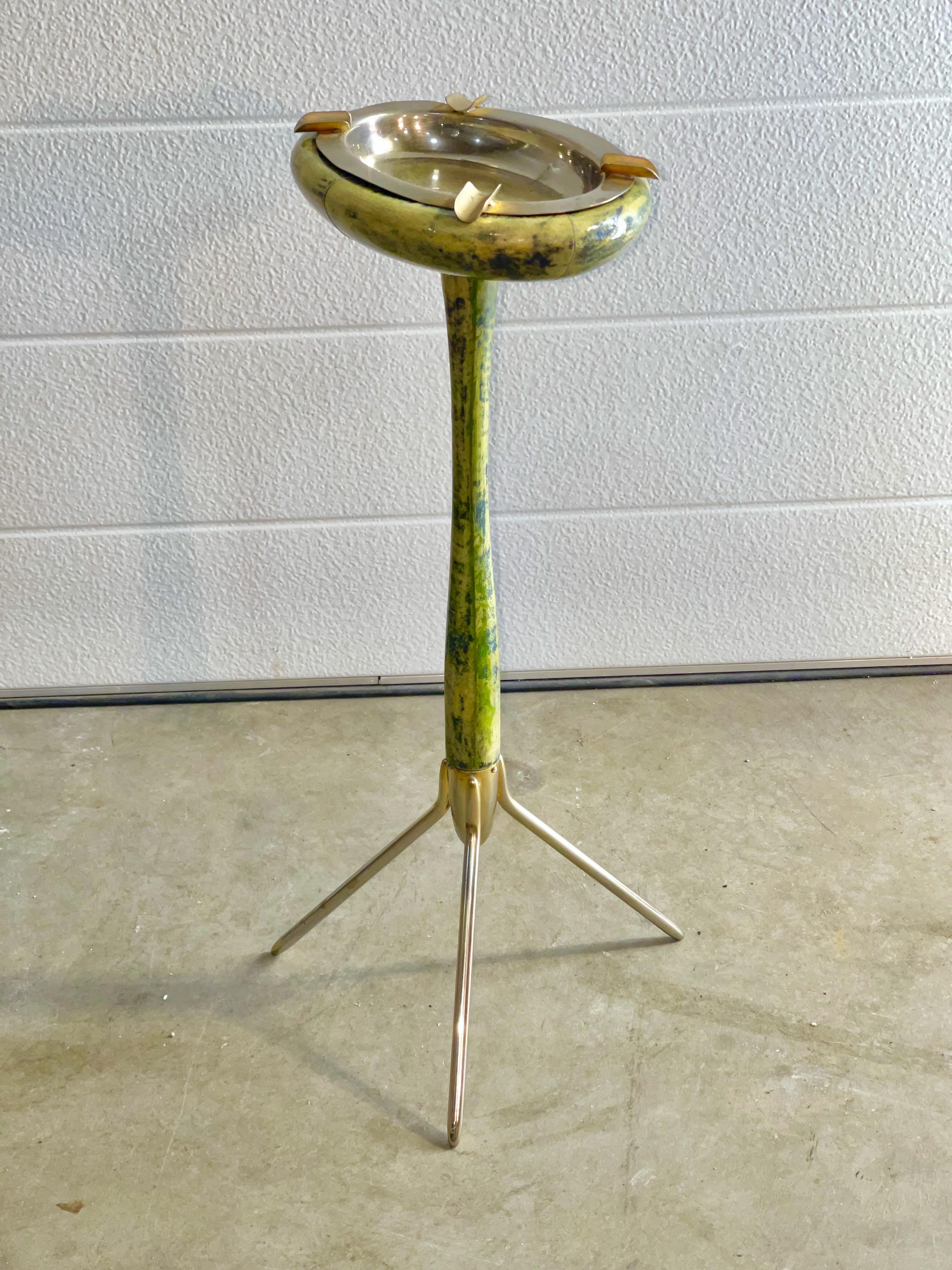 Aldo Tura 1960s standing ashtray or vide poche made of wood applied with lacquered goatskin in green pigment dye with dark speckles mounted in a solid brass tripod Stand. Brass finished removable ashtray. Residue of original Tura label present. A