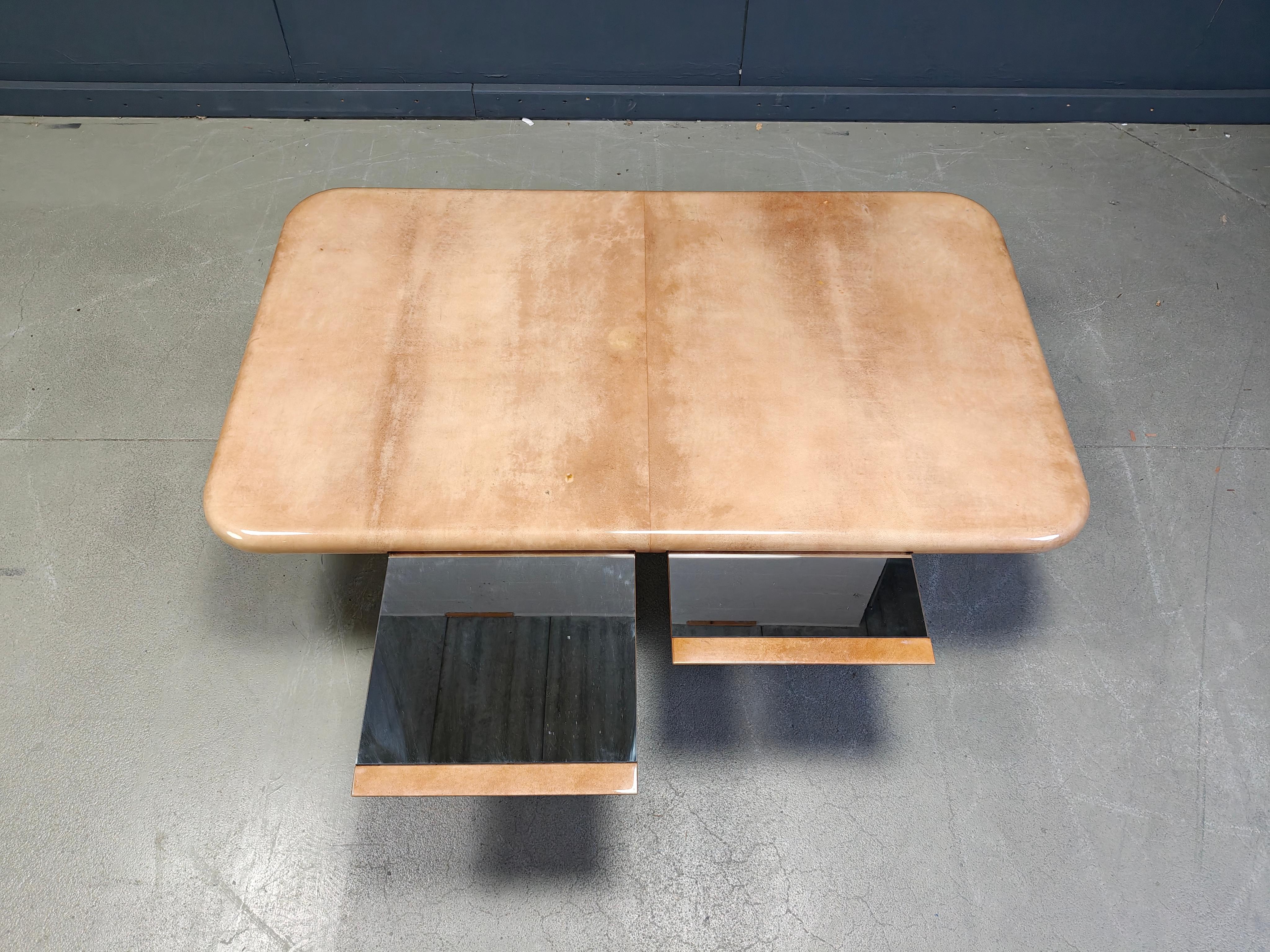 Rare table basse d'Aldo Tura présentant un plateau en peau de chèvre laquée monté sur une base en bois noir.

Il est doté de deux plateaux intégrés en miroir qui s'insèrent dans la partie supérieure et peuvent coulisser de part et d'autre, ce qui