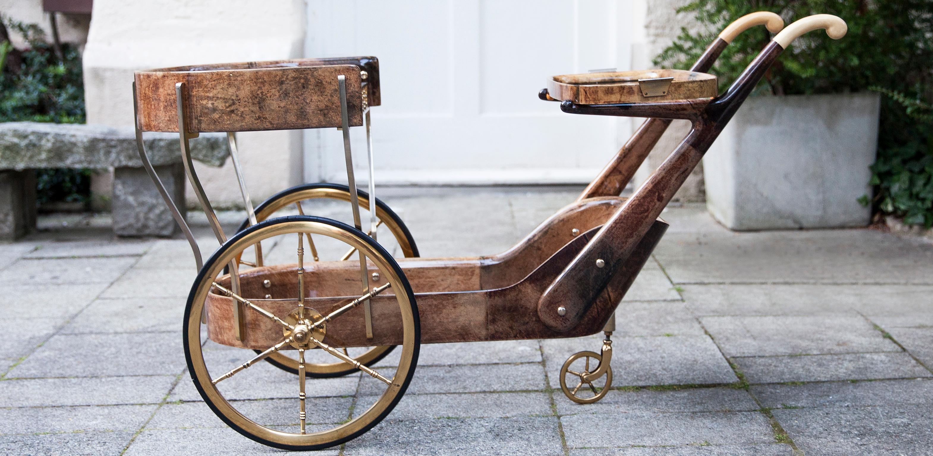 Gorgeous Aldo Tura Hollywood Regency style bar or serving cart by Aldo Tura, Milano, Italy, 1965. Brown lacquered goatskin with two glass tops and a serving tray with brass handles. Original brass wheels and brass applications. Excellent