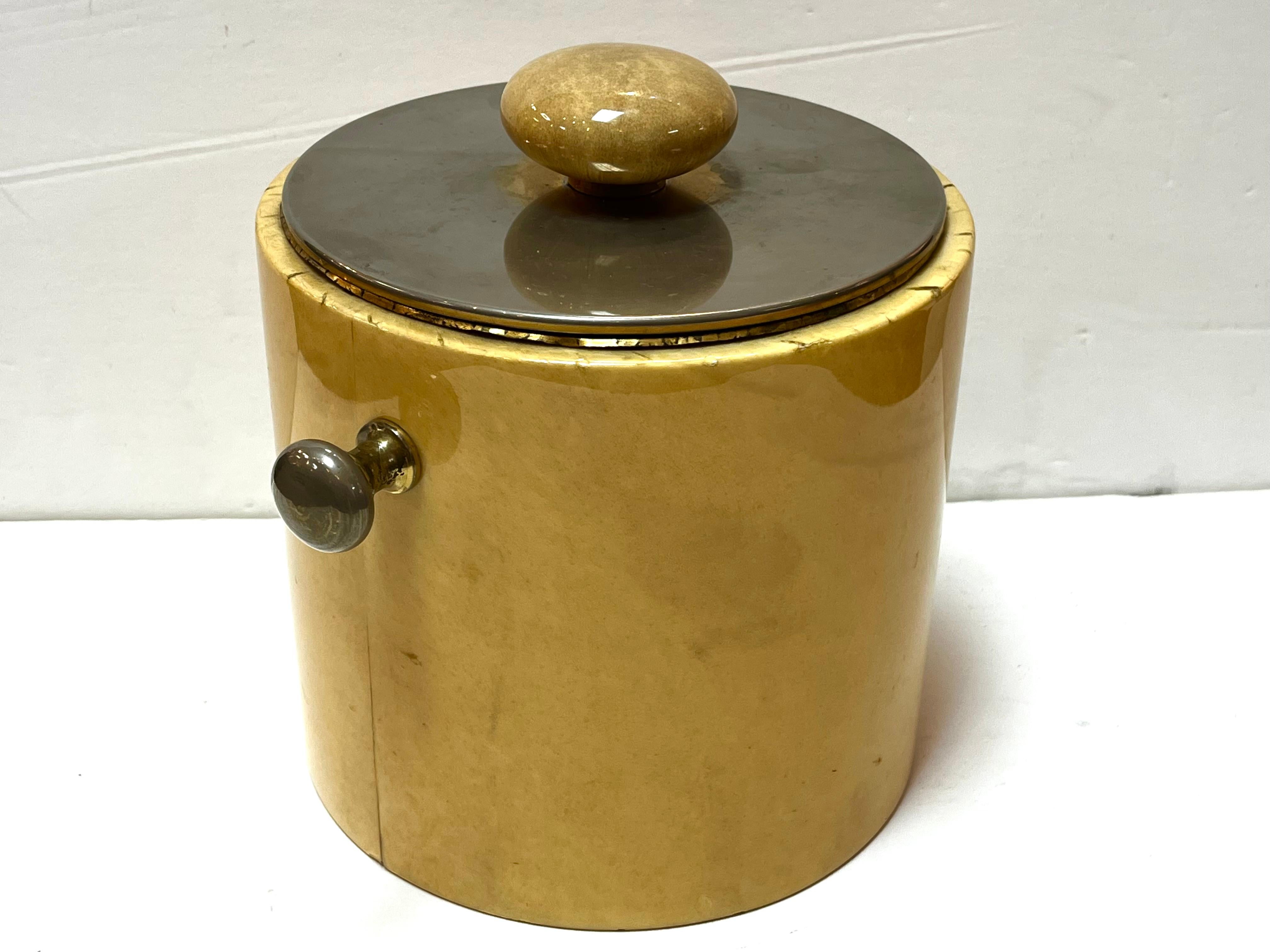 A mid century Aldo Tura ice bucket. Label on the bottom. This ice bucket features a metal lid with round handle as well as two smaller metal handles on either side of the ice bucket. From the artnet website, “Aldo Tura was an Italian furniture