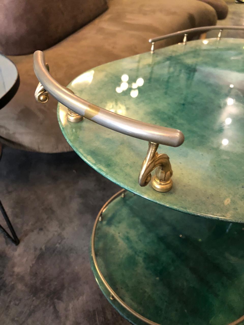 Beautiful Italian Mid-Century Modern bar trolley in shape of a pipe by Aldo Tura. The 2-tier trolley with metal ice bucket shows green goatskin cover. Wheels, covers and pulls are made in brass.