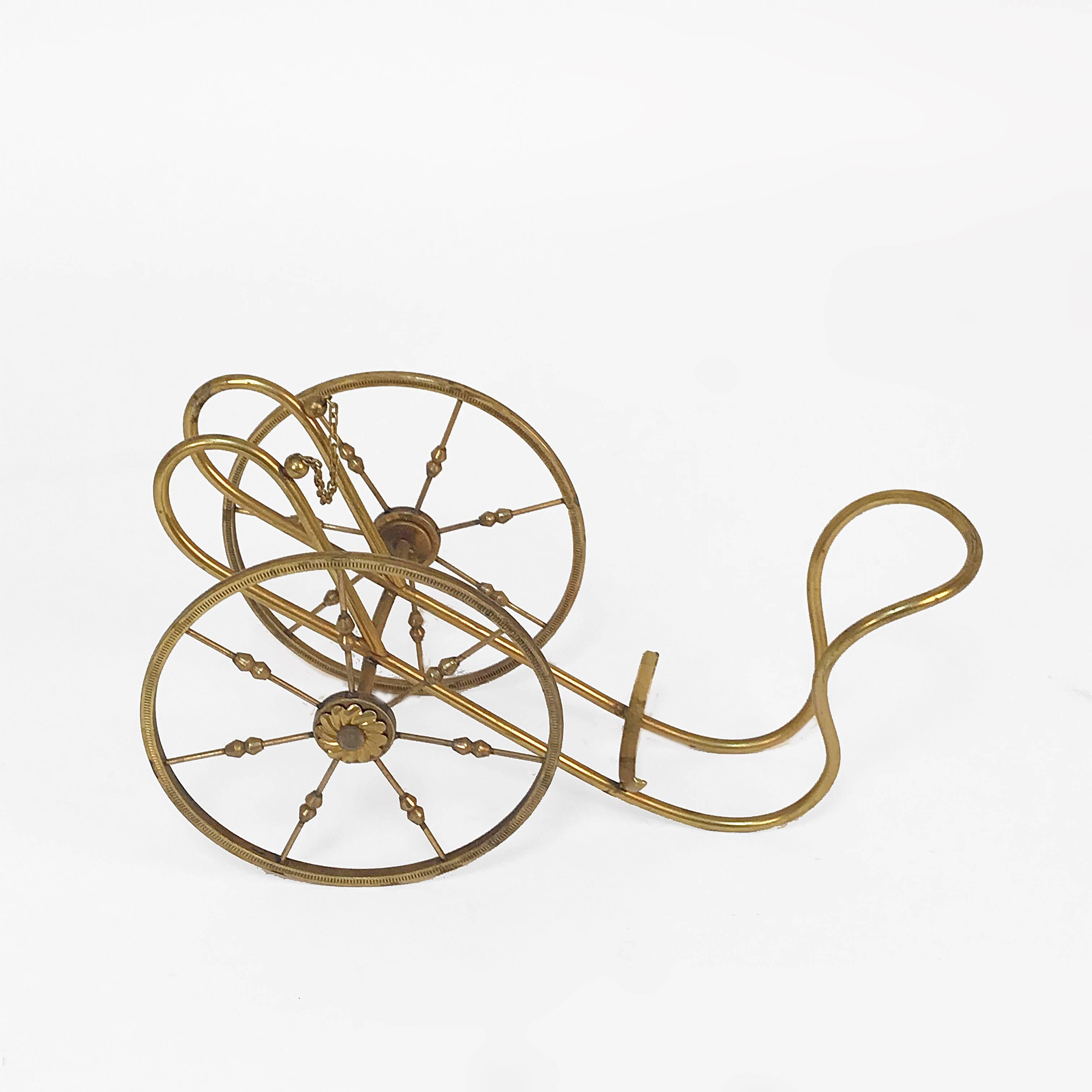 Bottle rack in gilded brass, Italy, 1950s by Aldo Tura.

This wine rack is very unique as the main structure is sustained by two neoclassical wheels, giving this classic piece a fun touch.

Perfect for a classic or neoclassic dining room.