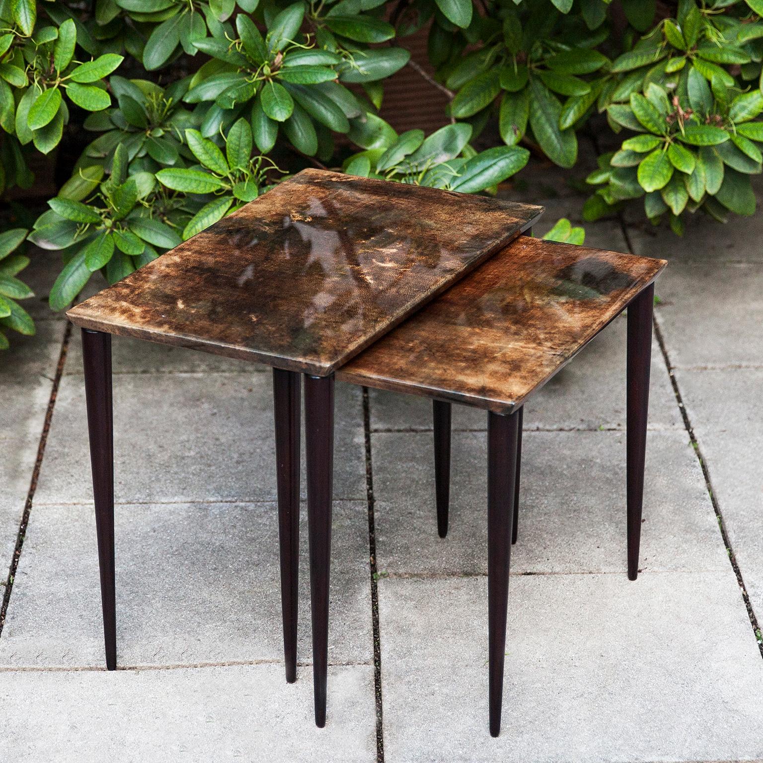 Set of two Aldo Tura nesting tables in lacquered brown goatskin and mahogany legs. This particular set was executed, circa 1960 and is in perfect condition. Along with artists like Piero Fornasetti and Carlo Bugatti, Aldo Tura (1909-1963) definitely