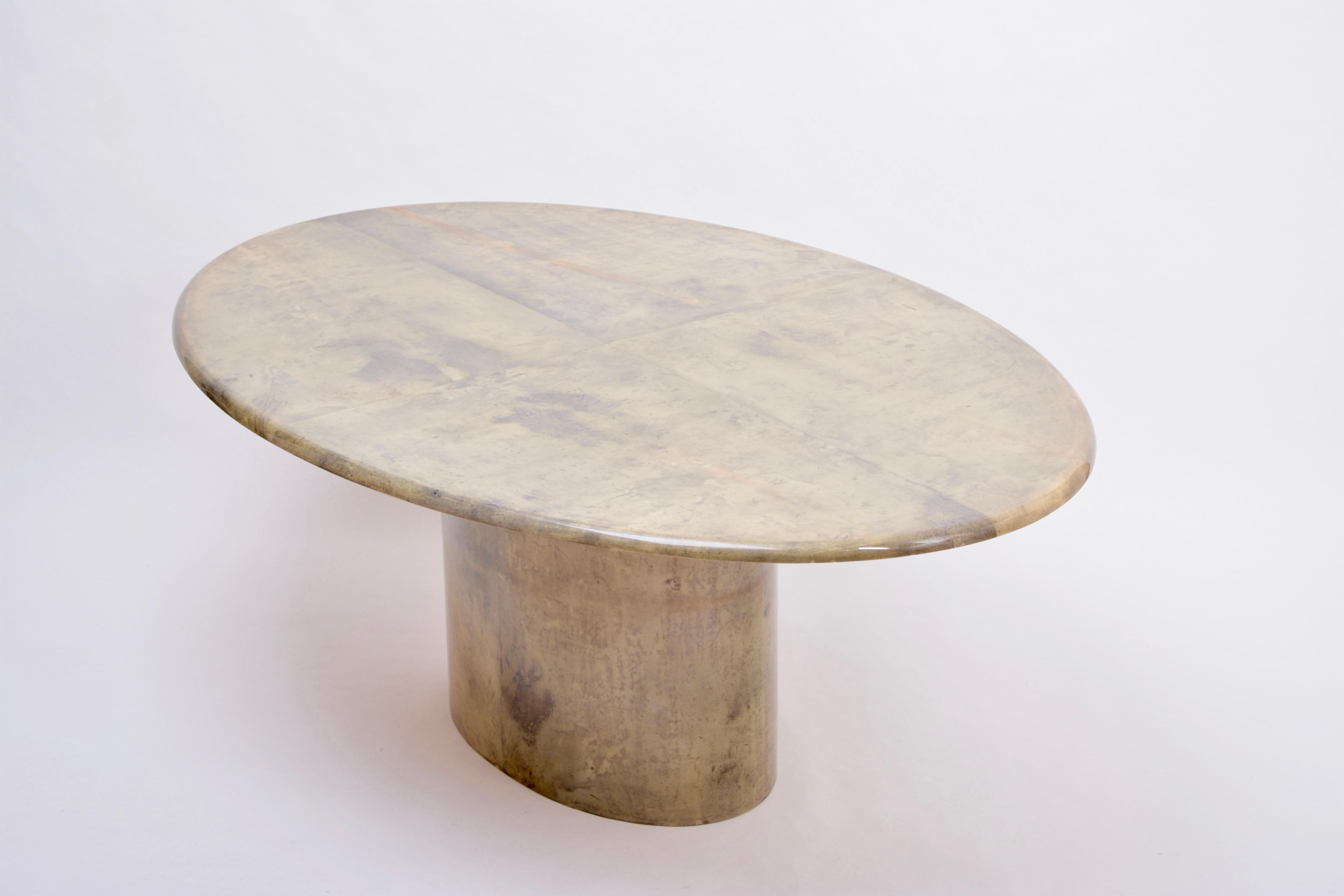 Oval dining table designed by Aldo Tura and produced in Italy in the 1970s. This dining table is a very strong example of his work, simple in form, with a soft curved oval top affixed to an oval pedestal base. The ethereal lacquered goatskin gives a