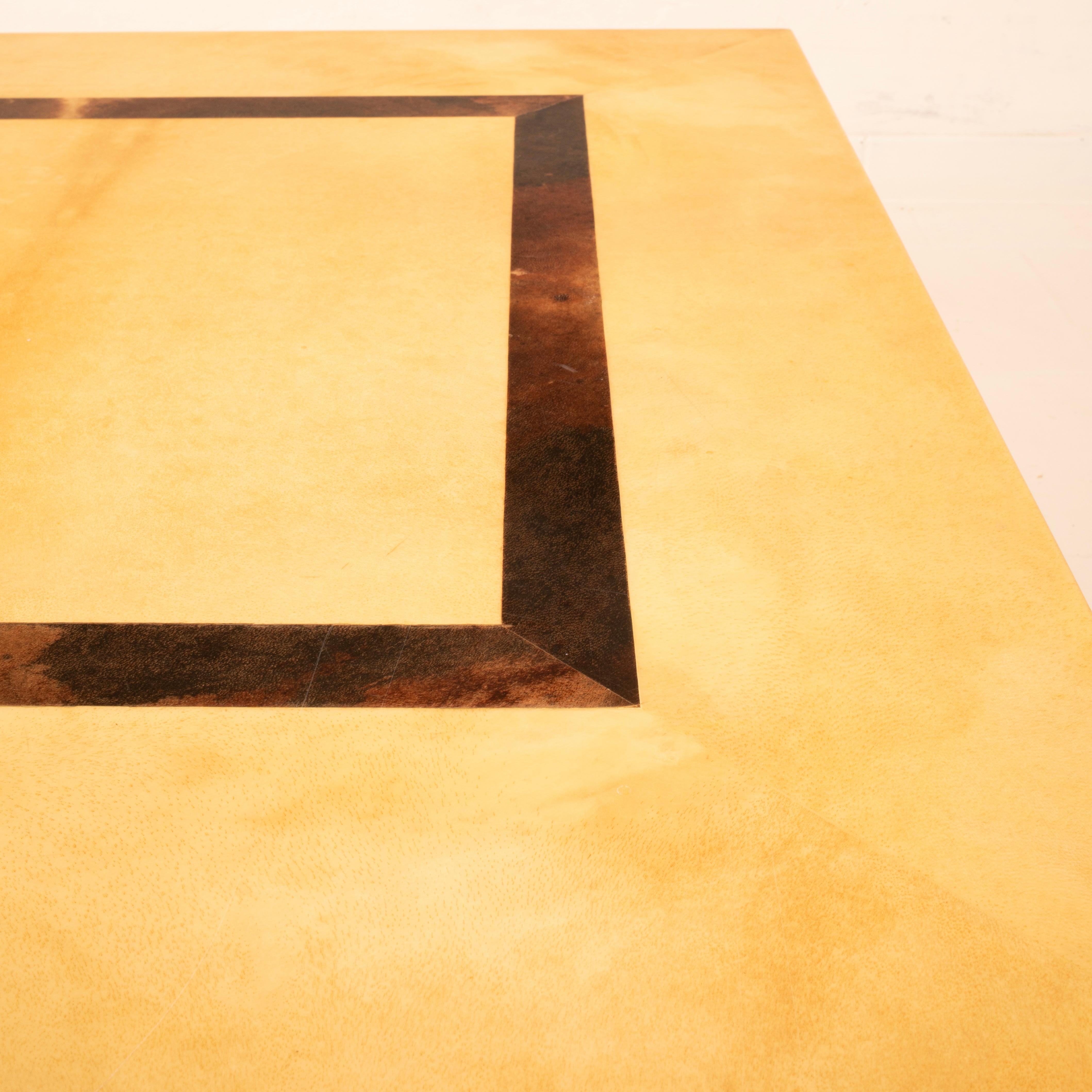 Low coffee table designed by Aldo Tura in the 1960s, crafted in parchment—specifically hand-dyed goatskin—in two different tones: a warm, luminous light finish for the main surface and a darker, almost burnt parchment for the inset central geometric