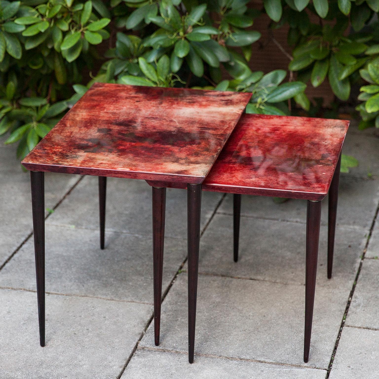 Set of two Aldo Tura nesting tables in lacquered red goatskin and mahogany legs this particular set was executed, circa 1960 and is in perfect condition. Along with artists like Piero Fornasetti and Carlo Bugatti, Aldo Tura (1909-1963) definitely