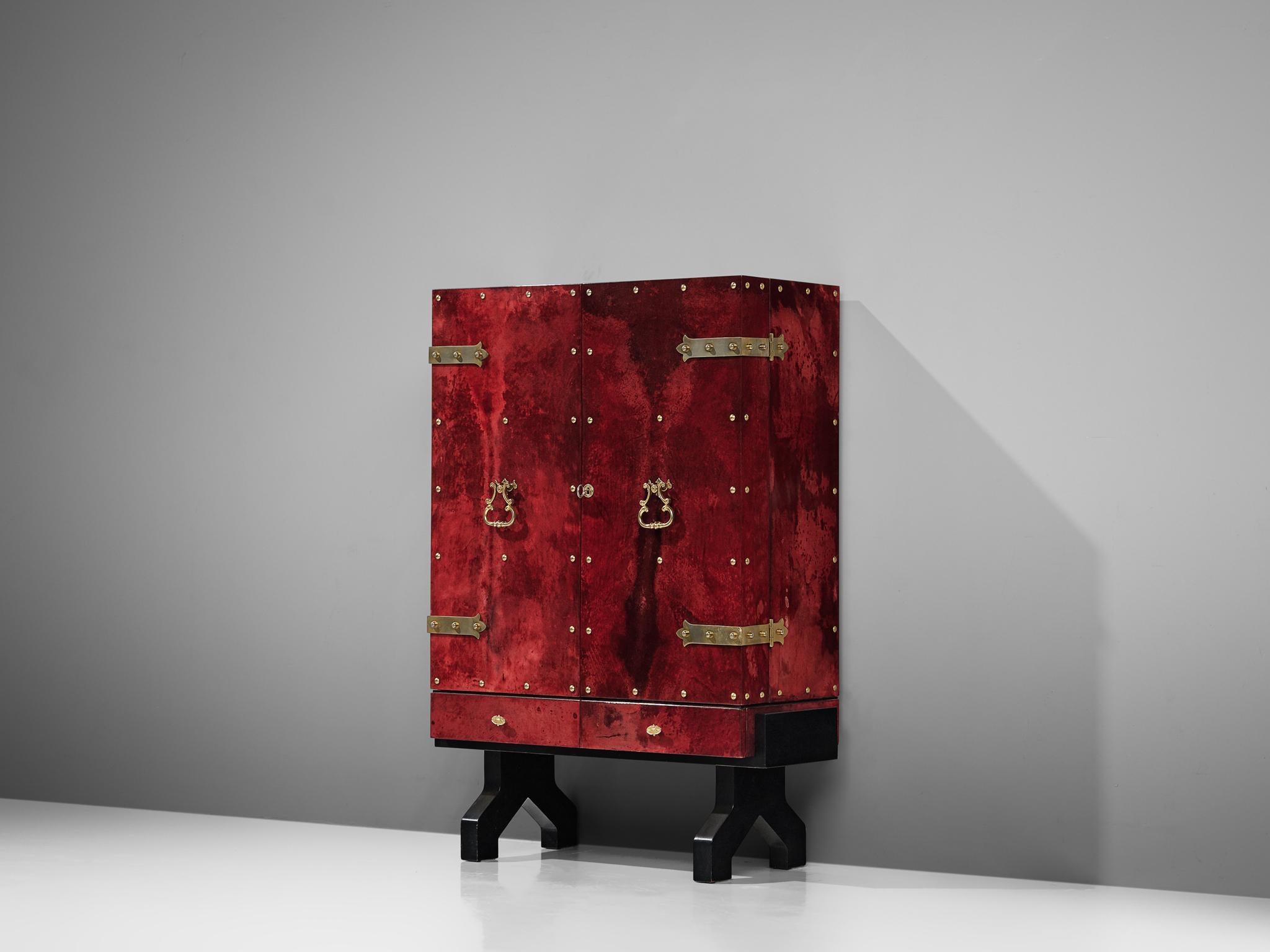 Aldo Tura, cabinet, wood, glass, metal and parchment, Italy, 1950s.

This is a cabinet designed by Aldo Tura that is meant to function as a dry bar or liquor cabinet. The wooden base holds a cabinet that's covered in a nice deep red parchment. The