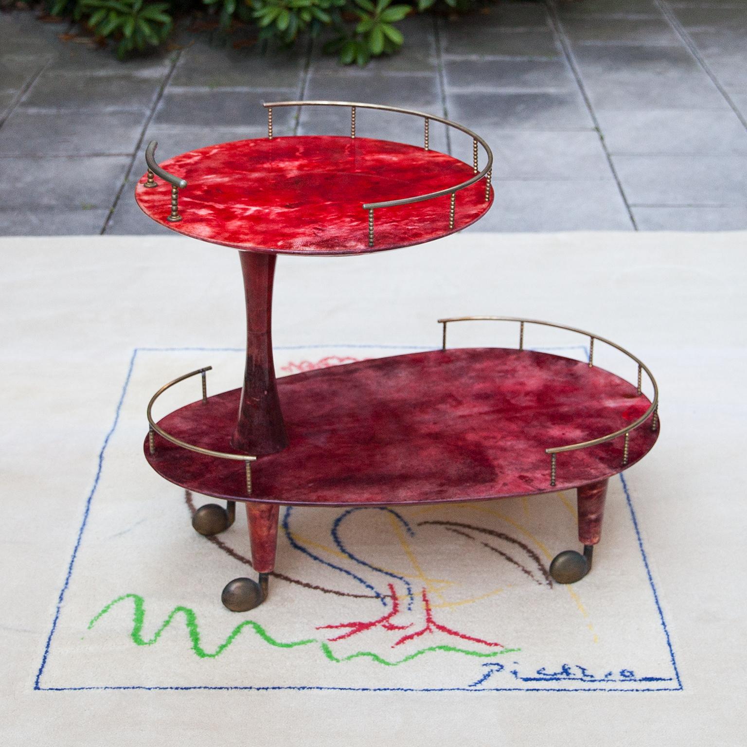 Elegante carrito de bar Aldo Tura de dos pisos realizado en pergamino rojo y varillas de latón en perfecto estado.

Junto con artistas como Piero Fornasetti y Carlo Bugatti, Aldo Tura (1909-1963) pertenecía definitivamente a los inconformistas del