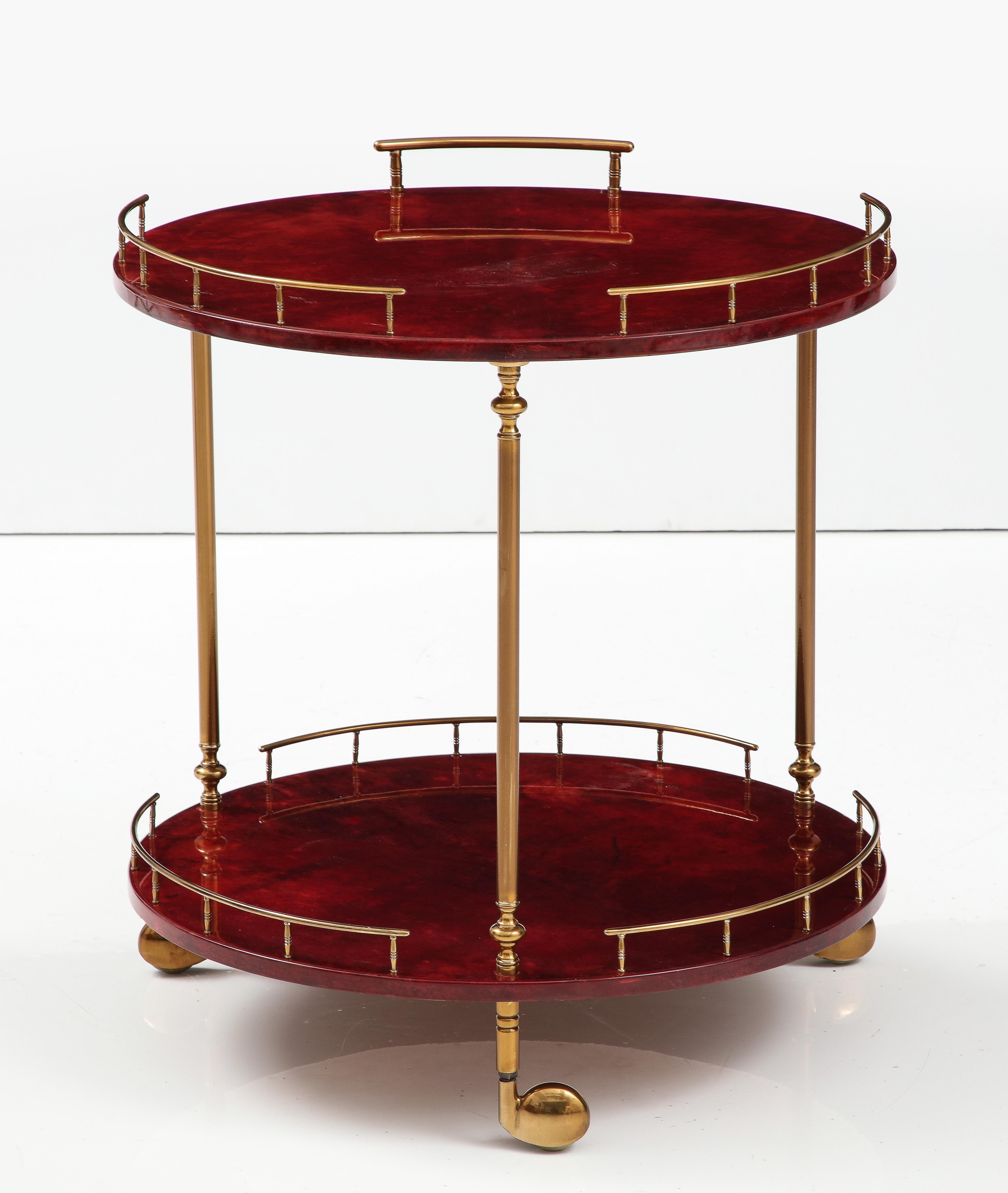 Modern classic 2 tier bar cart by Aldo Turn. The 2 level cart features Ruby Red/Cranberry dyed goatskin all supported by brass supports and castors. All mint restored.