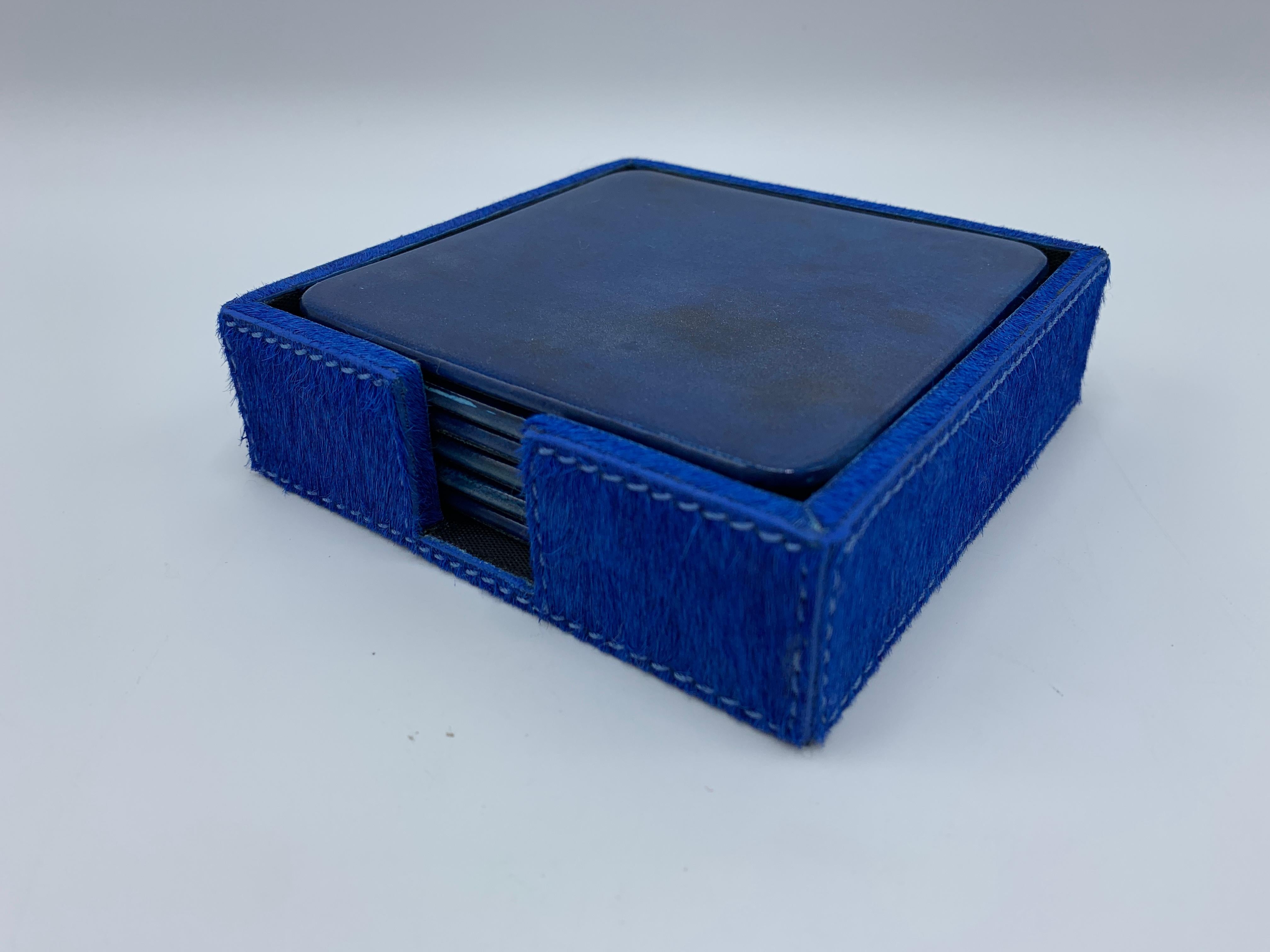 Listed is a gorgeous, set of six, Aldo Tura style blue lacquered goatskin parchment coasters. The set has a complimentary blue dyed hide coaster tray. Seven pieces total. Backing is a black, water-resistant nylon material. Each coaster measures 4in