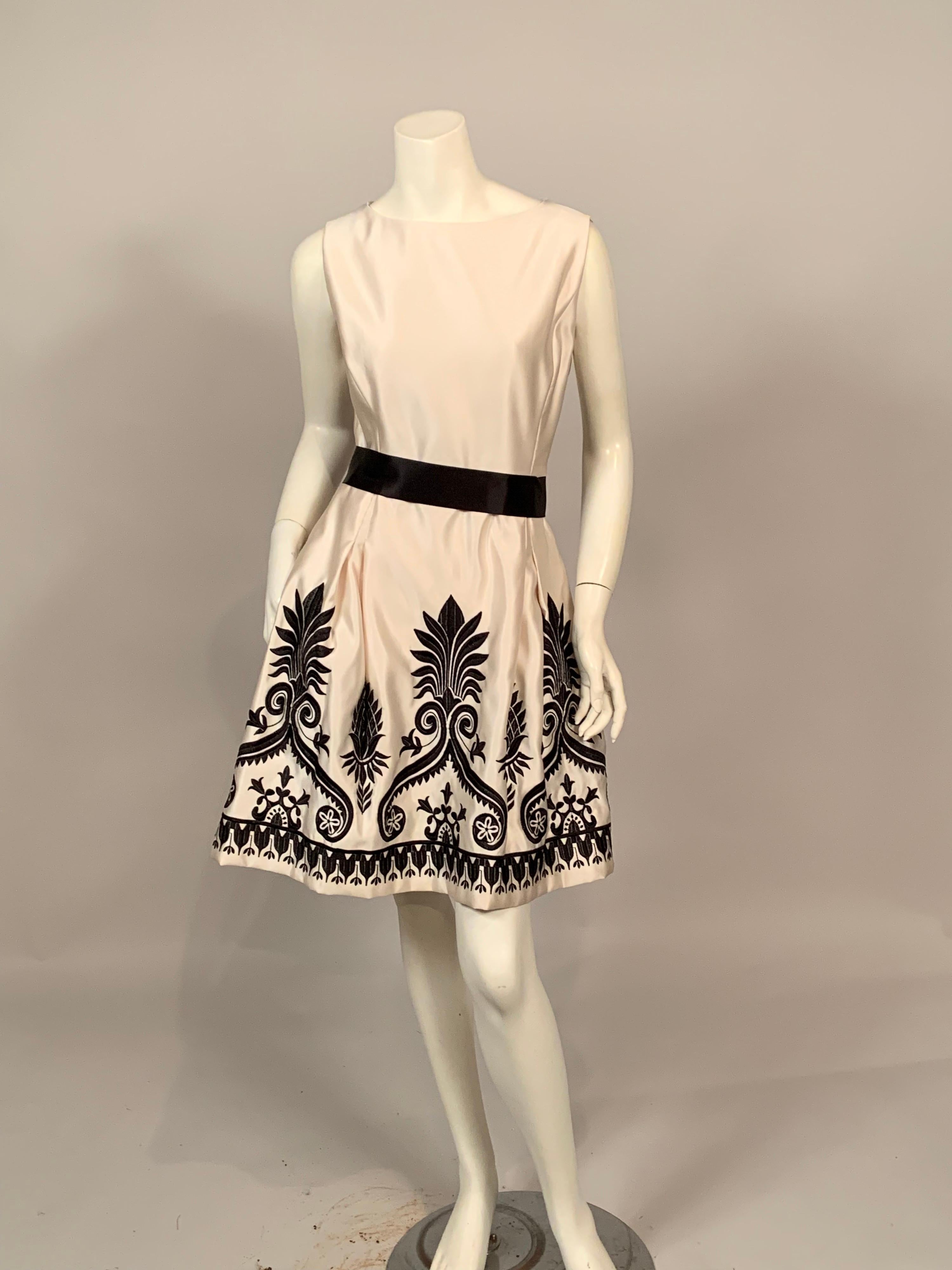 The high contrast of black and white always creates a dramatic look and this dress is a classic design with striking embellishment. The dress has a round neckline, sleeveless bodice, a fitted waist accented with a wide black satin ribbon belt. The