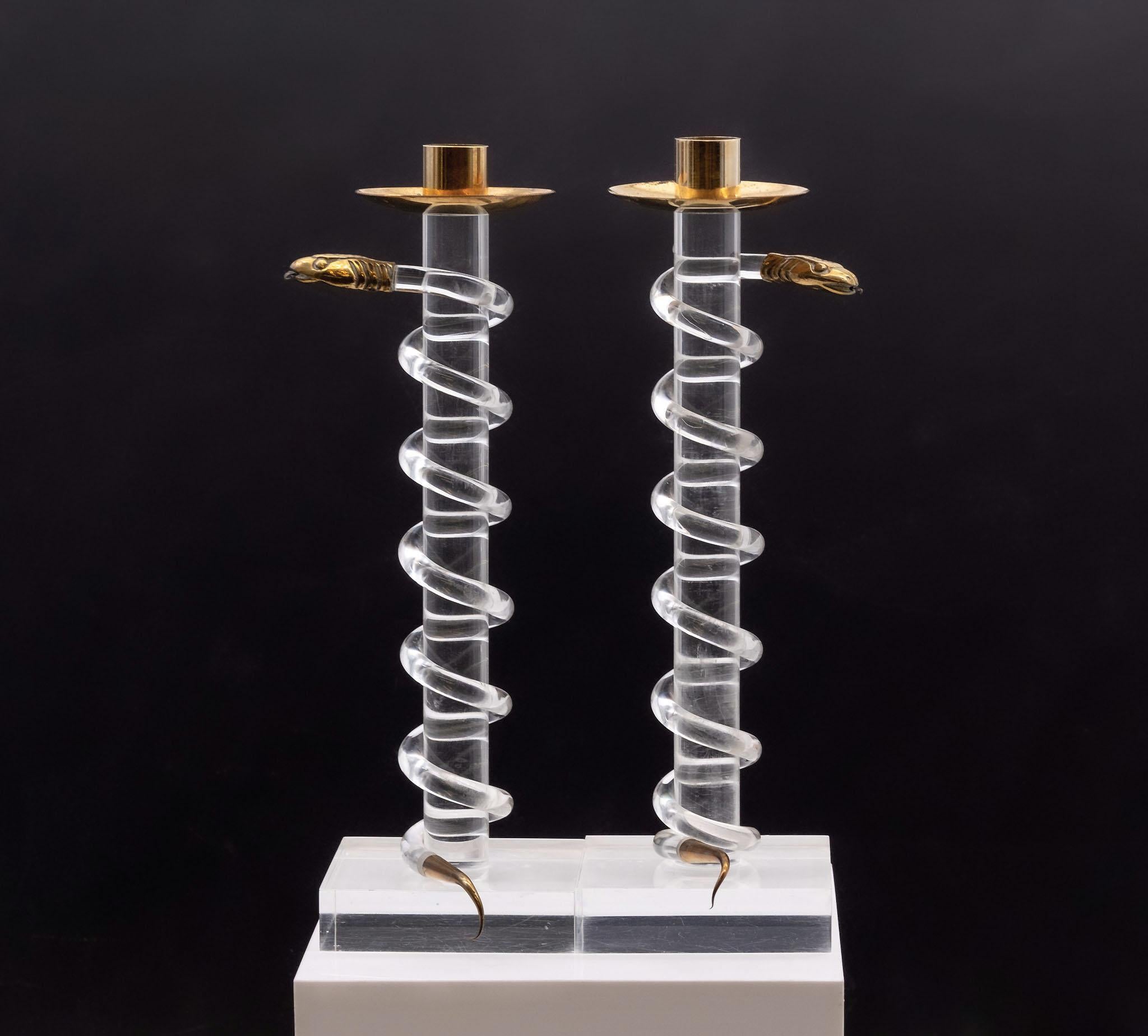 Pair of Lucite and brass serpent snake candlesticks by Italian designer Alessandro Albrizzi. Circa 1970s.

The candlesticks have a strong sculptural presence. Standing on plinth bases, the snakes scroll sinuously up the stems. The snakes can be