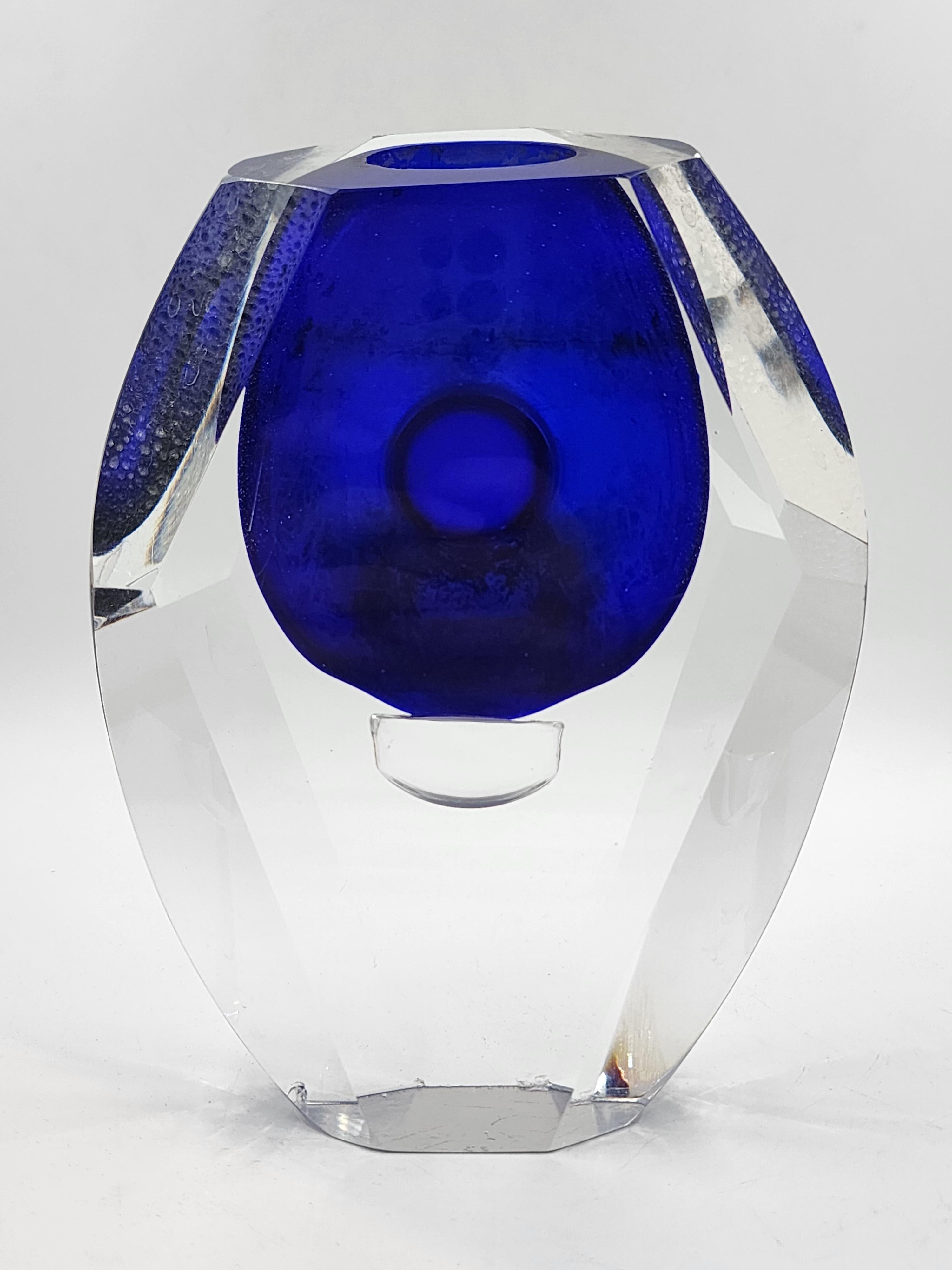 Art Glass Vase by Alessandro Mandruzzato
This art glass vase, attributed to Alessandro Mandruzzato, features a faceted geometric design with a shape resembling an irregular octahedron. It is crafted of thick clear glass, enclosing a vibrant cobalt
