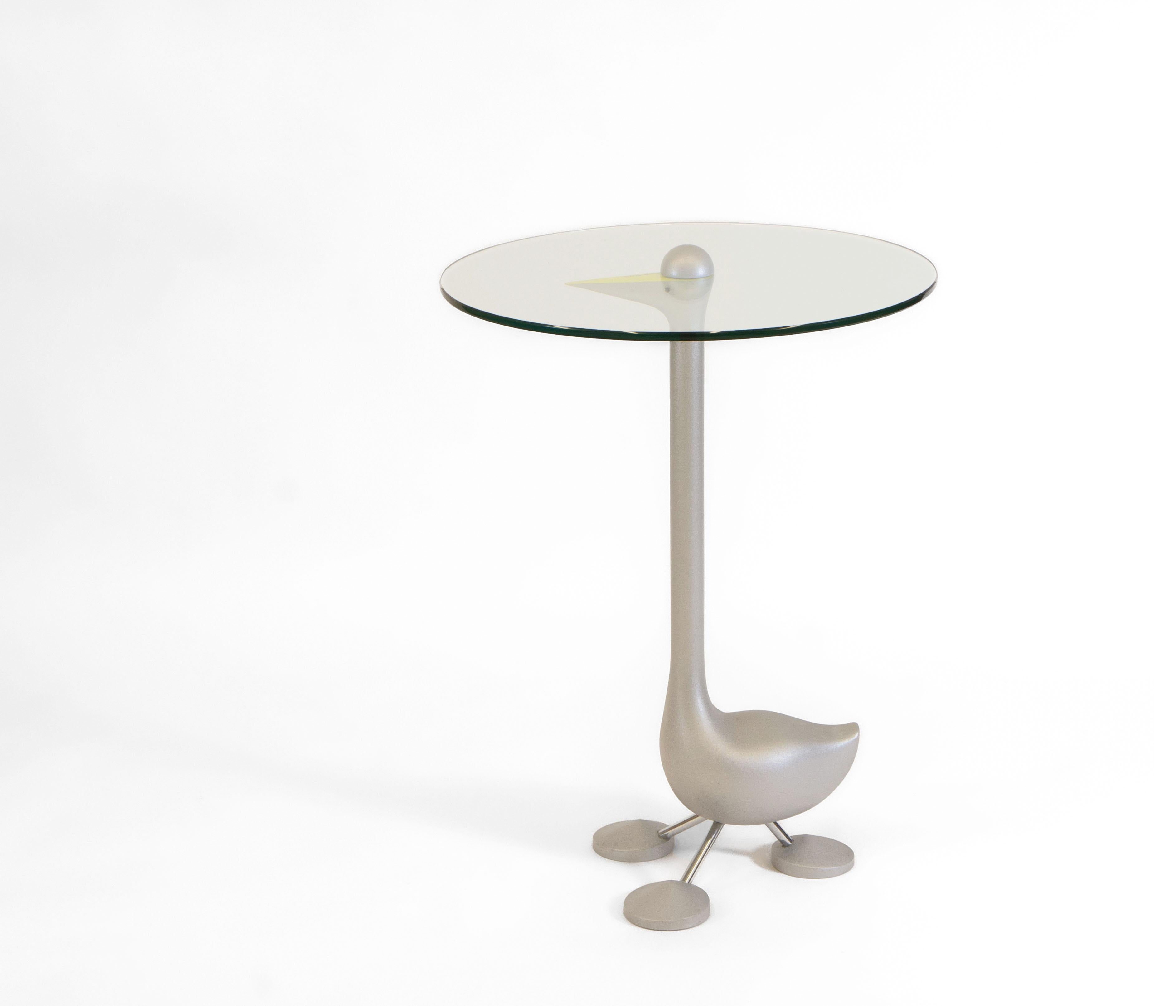 A signed Sirfo Goose Table designed by Alessandro Mendini (1931- 2019) in 1986 for Zanotta Edizioni. circa 1980s.

The frame is sandblasted cast aluminium, with a yellow painted beak. The clear glass is tempered and 6mm thick.

Intended as works