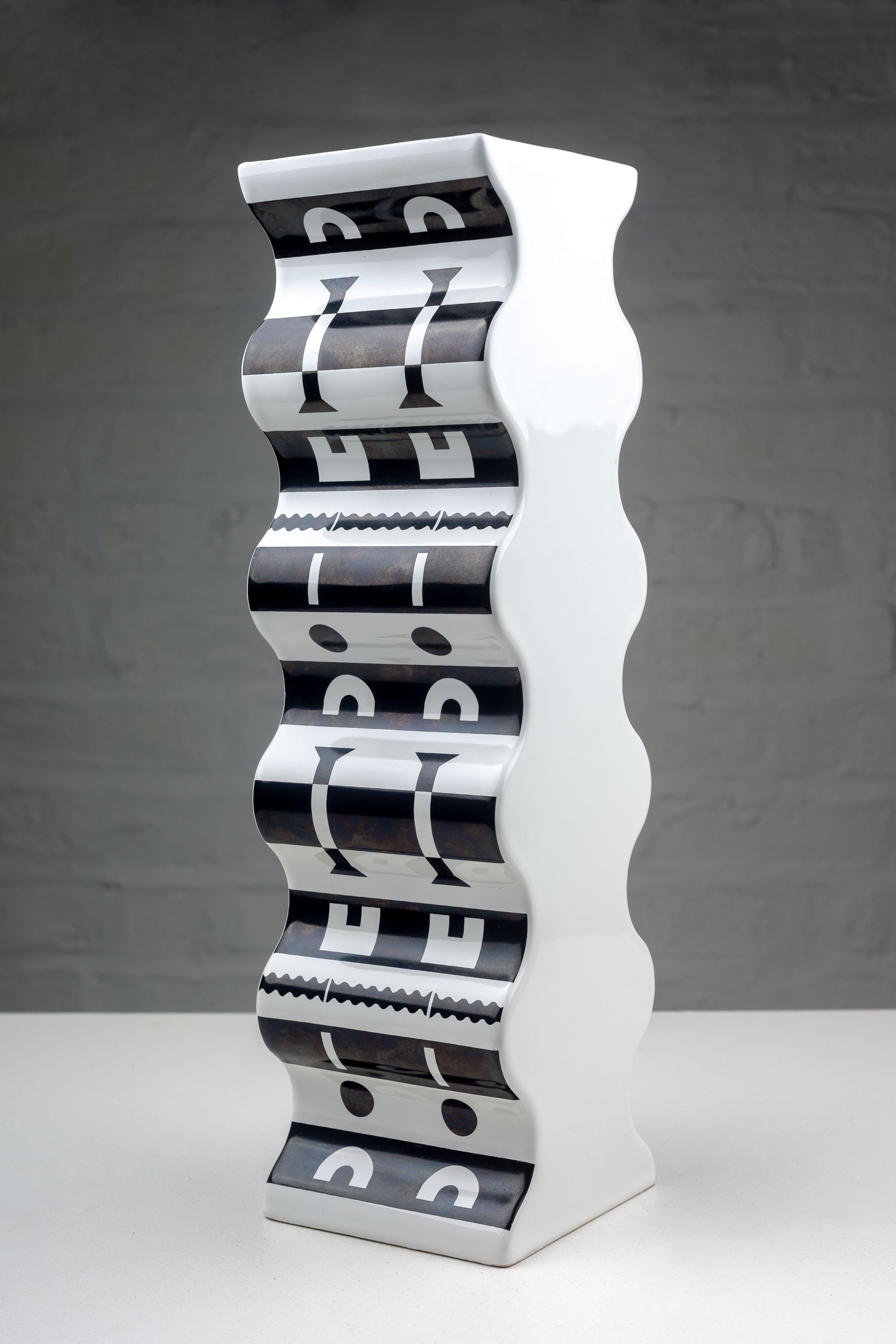 Alessandro Mendini a créé ce vase évocateur pour le Studio Alchimia en 1988. D'une hauteur imposante, semblable à une colonne, le vase présente une série de contours ondulés et sinueux qui donnent une illusion de mouvement et de fluidité. Il s'agit