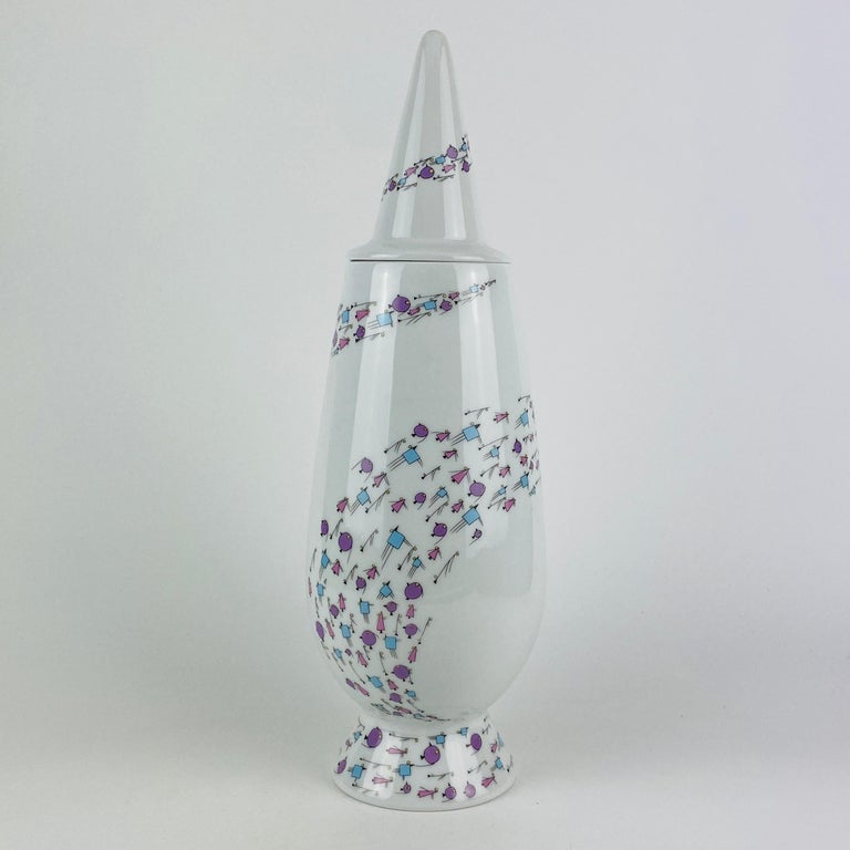 This Tendentse Alessi vase with lid is part of the 100% make-up limited series of 10.000. This series consists of 100 different vases and 100 different designers/decorators. 

This vase in particular is designed by Alessandro Mendini and decorated