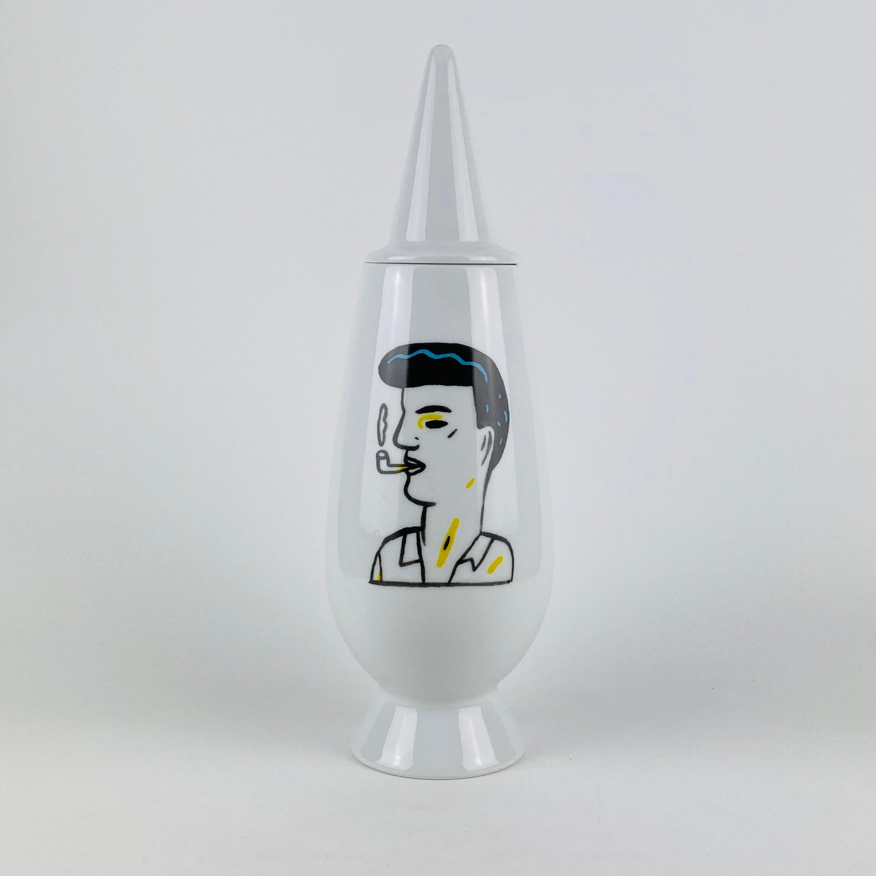 Diese Tendentse Alessi Vase mit Deckel ist Teil der auf 10.000 Exemplare limitierten Serie 100% Make-up. Diese Serie besteht aus 100 verschiedenen Vasen und 100 verschiedenen Designern/Dekorateuren. 

Diese Vase wurde von Alessandro Mendini