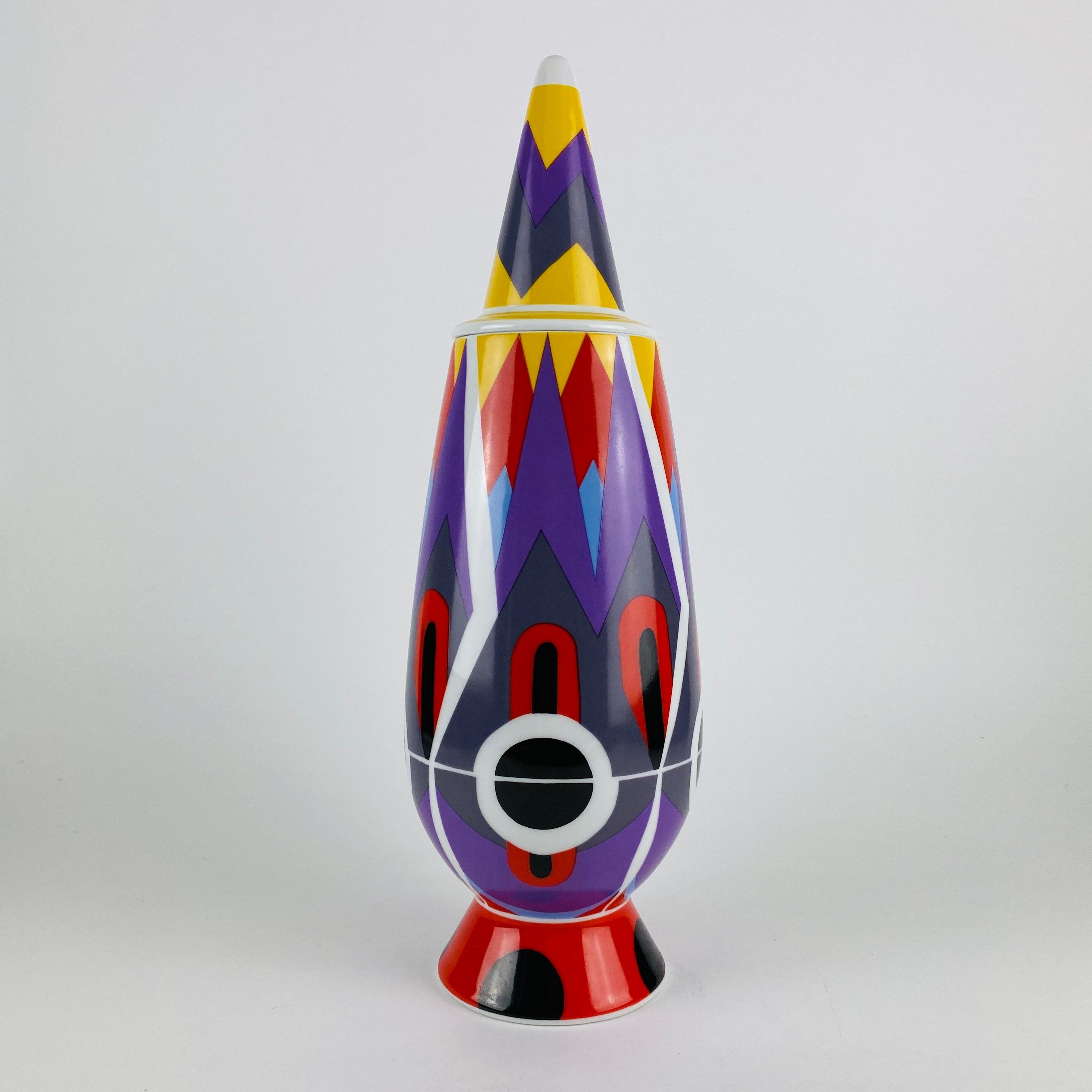 This Tendentse Alessi vase with lid is part of the 100% make-up limited series of a 100 reproductions. This series consists of 100 different vases and 100 different designers/decorators. 

This vase in particular is designed by Alessandro Mendini
