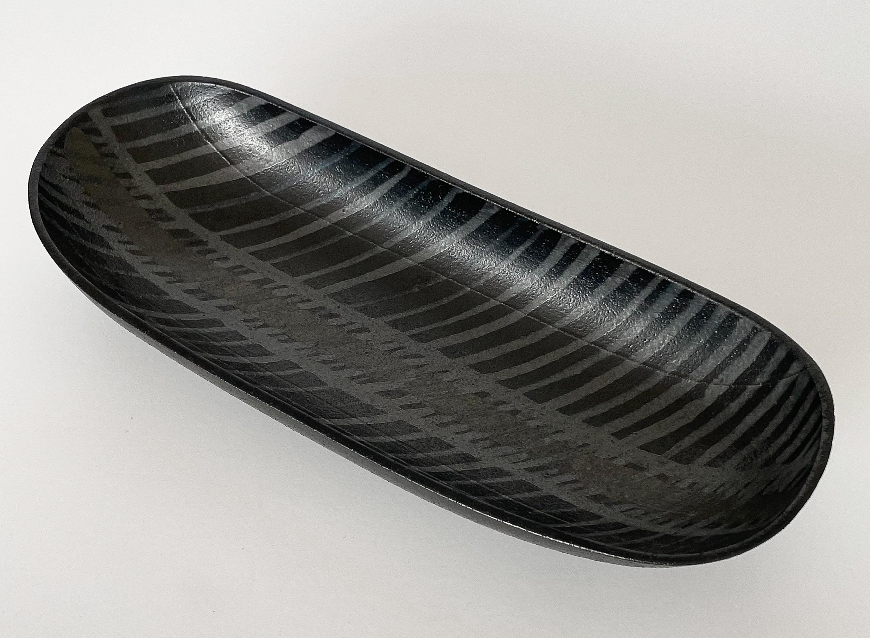 An uncommon black and gray centerpiece low bowl by Alessio Tasca, Italy circa 1970s. This modern black ceramic elongated bowl features an abstract striped design within the interior in gray and bronze colors. Stamped and retains the original paper