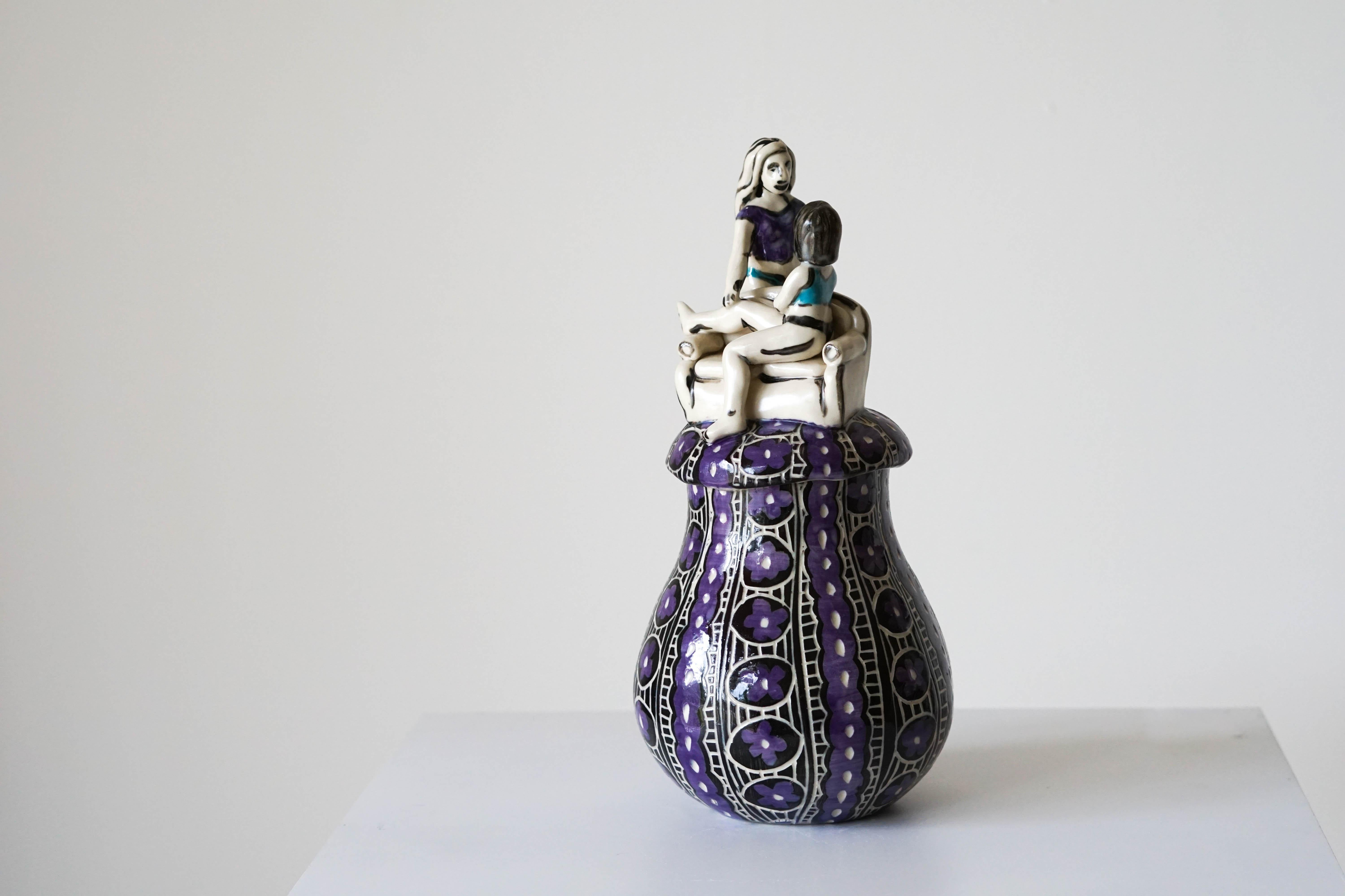 Volver a casa
Jarra escultórica de porcelana con detalles esgrafiados bajo vidriado


Esta jarra escultórica muestra a dos mujeres que se miran en un ambiente doméstico, señalado por la silla de la figura sentada y el dibujo de la jarra que hace
