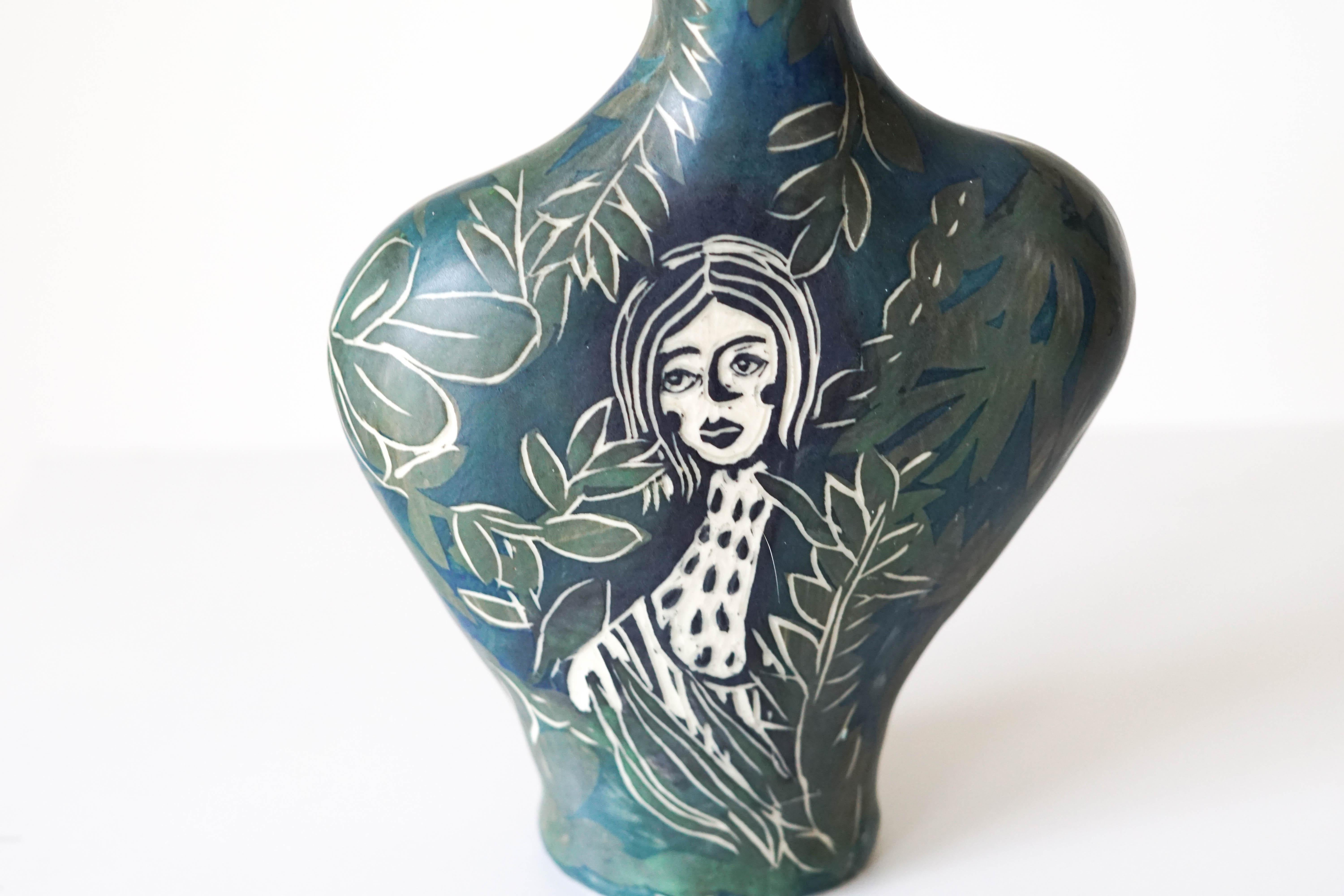 Earth needs us both
Porcelain vase with underglaze Sgraffito detailing.

This vase is a derivative of my Portrait collection; the vase features a woman on each side, one with a fire at her throat, and the other with a pattern, which may be