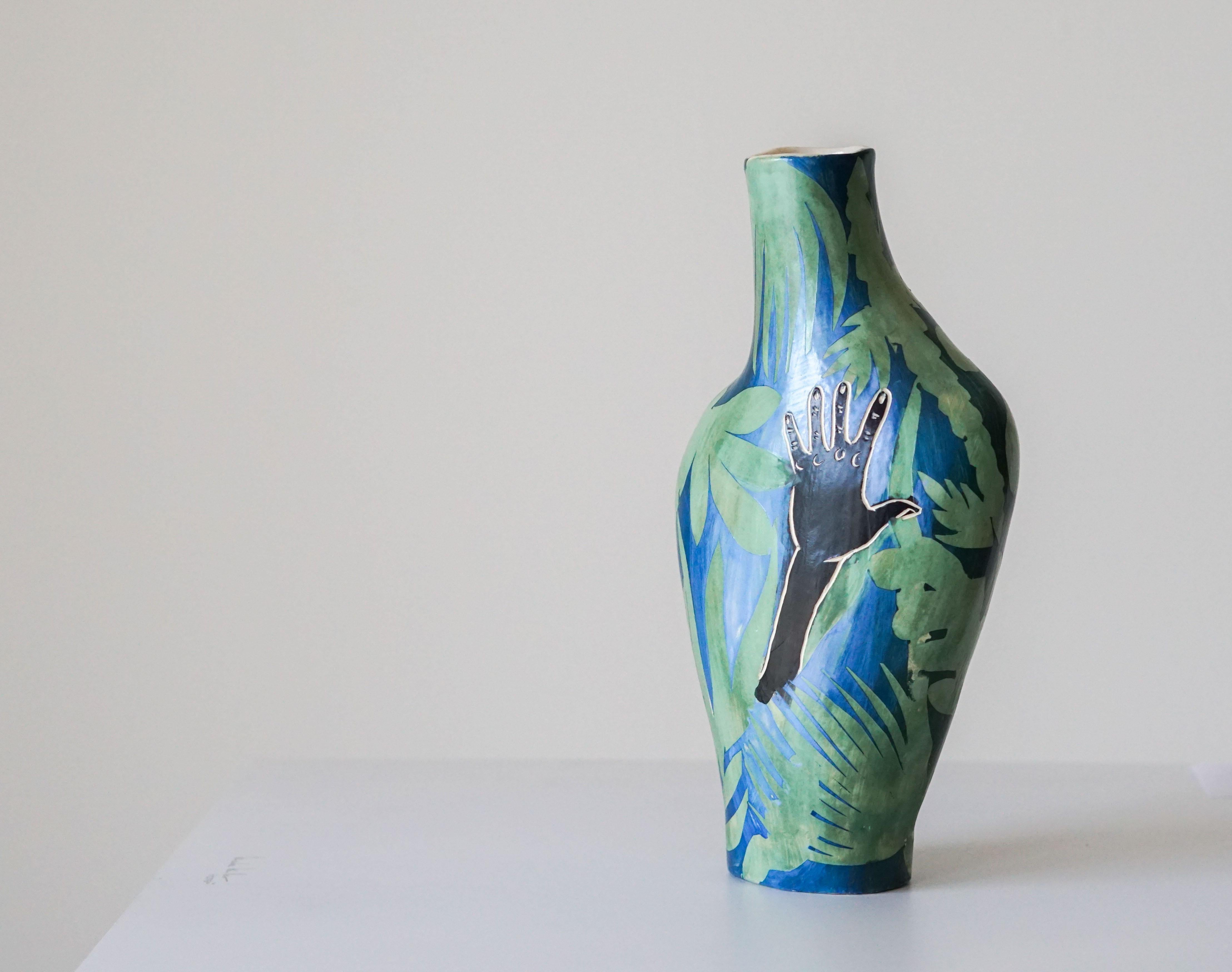 Helping Hand
Ceramic vase with underglaze Sgraffito detailing

This ceramic vase features lush, vibrant plant forms. On each side, a hand emerges as if to reach for something. The title references both the vulnerability of the earth and humanity and