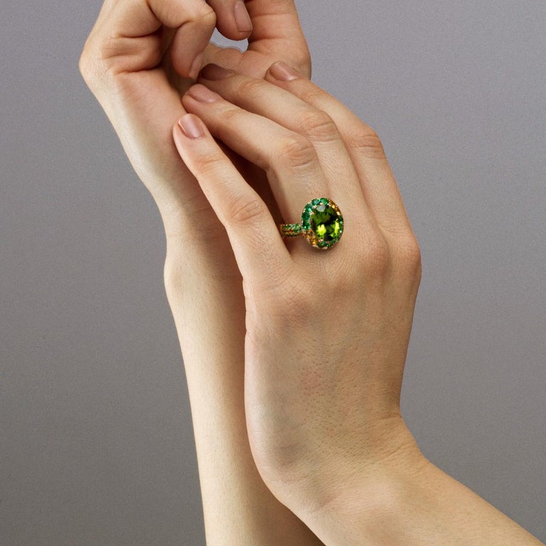 Alex Jona design collection, hand crafted in Italy, 18 Karat yellow gold ring, centering an oval peridot weighing 5.84 carats, surrounded by 70 tsavorites weighing 3.82 carats, 6 orange sapphires weighing 0.19 carats and 10 yellow sapphires weighing