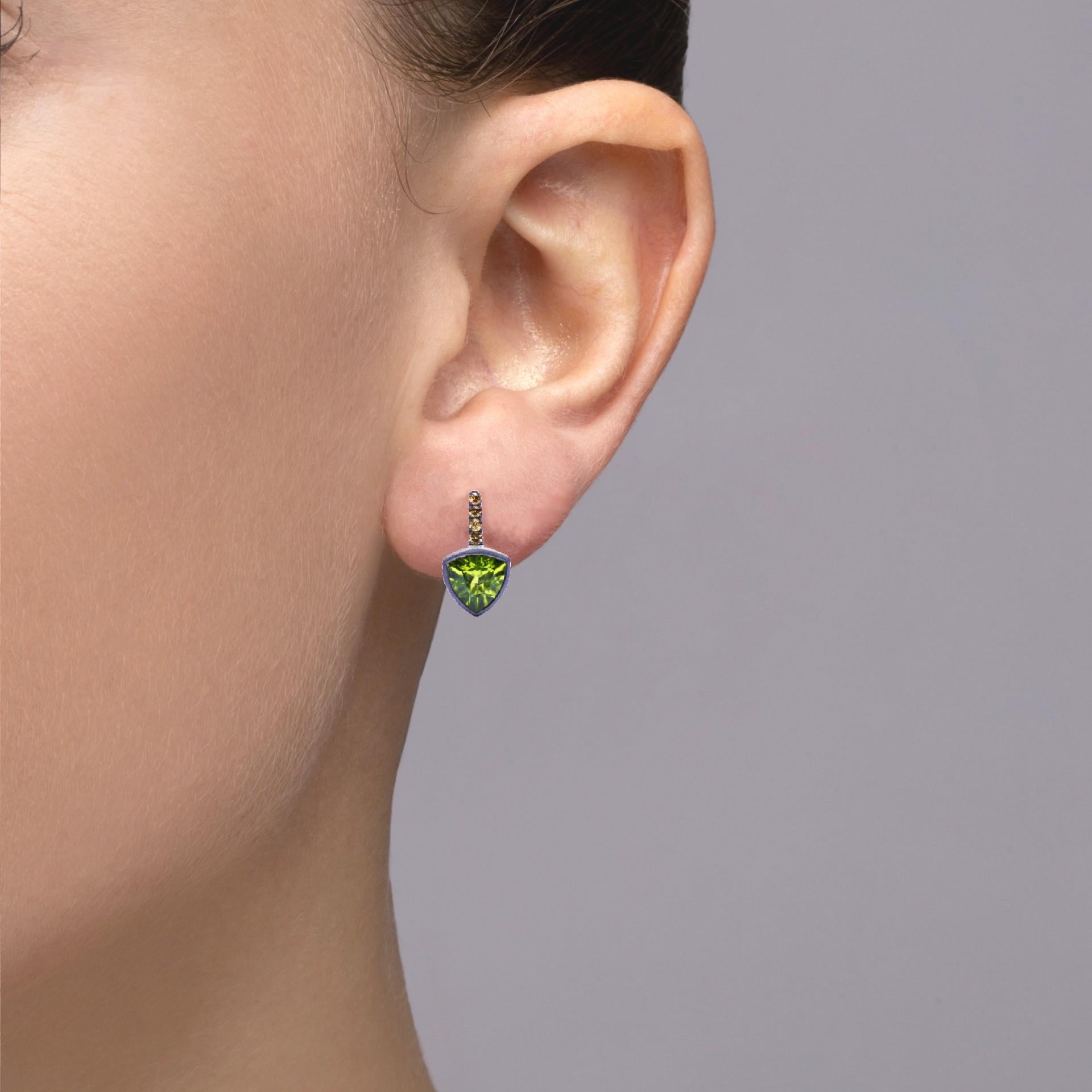 Alex Jona design collection, hand crafted in Italy, 18 karat white gold stud earrings with black rhodium set with two trillion cut peridots weighing 2.54 carats in total, surrounded by 0,15 carats of yellow sapphires.
Dimensions : H 0.57in/14.59mm,