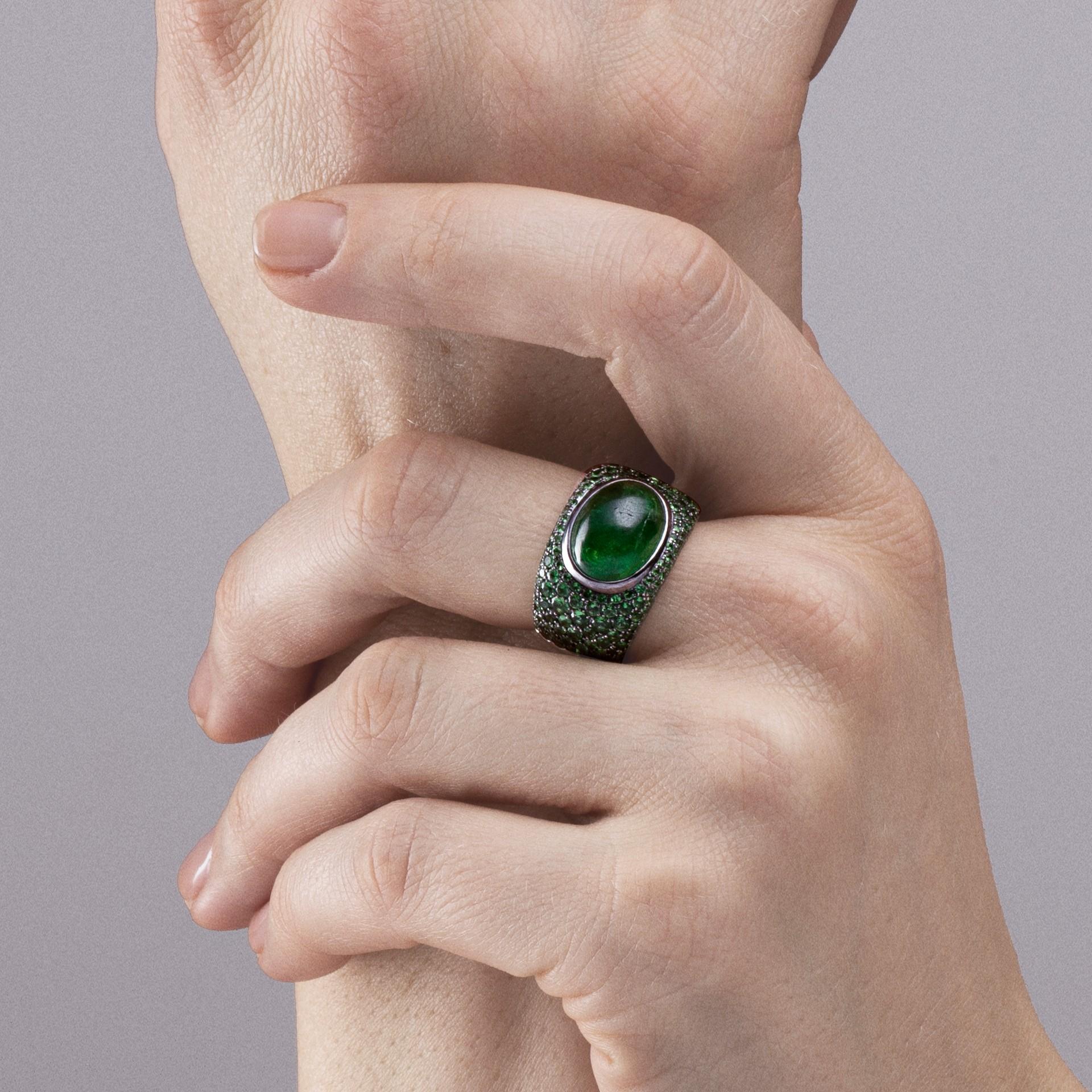 Anello a fascia in oro bianco 18 carati della collezione Alex Jona, realizzato a mano in Italia, con una tsavorite cabochon del peso di 7,30 carati e un pavé di tsavorite del peso totale di 2,59 carati.
Dimensioni: H 1 in x L 0,54 in x P 0,86 in -