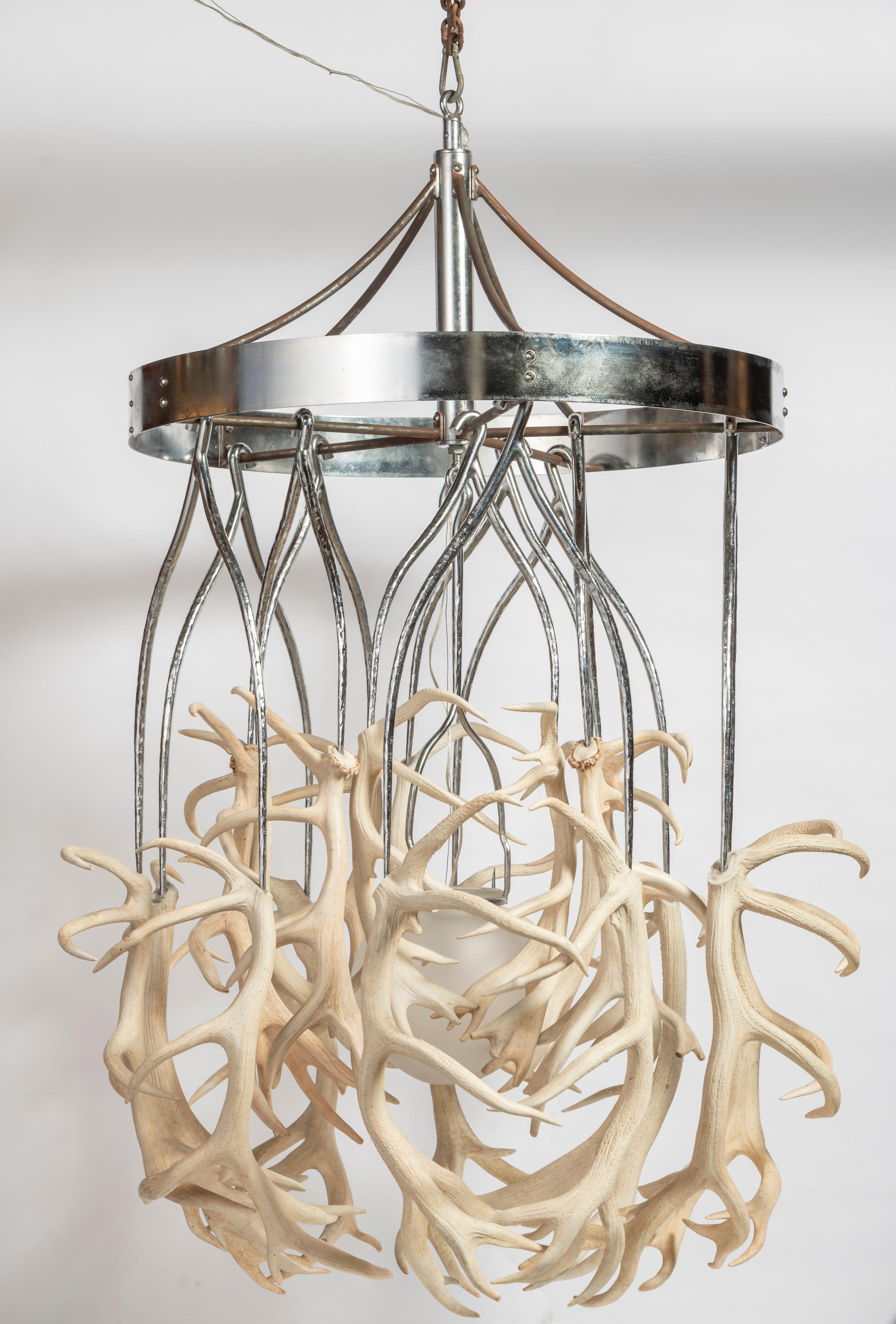 Alex Randall is an award-winning lighting designer based in London. The Antler Chandelier is crafted with ten pairs of humanely sourced red deer antlers, hanging from giant forged steel and chrome wishbone shaped hooks forming a 