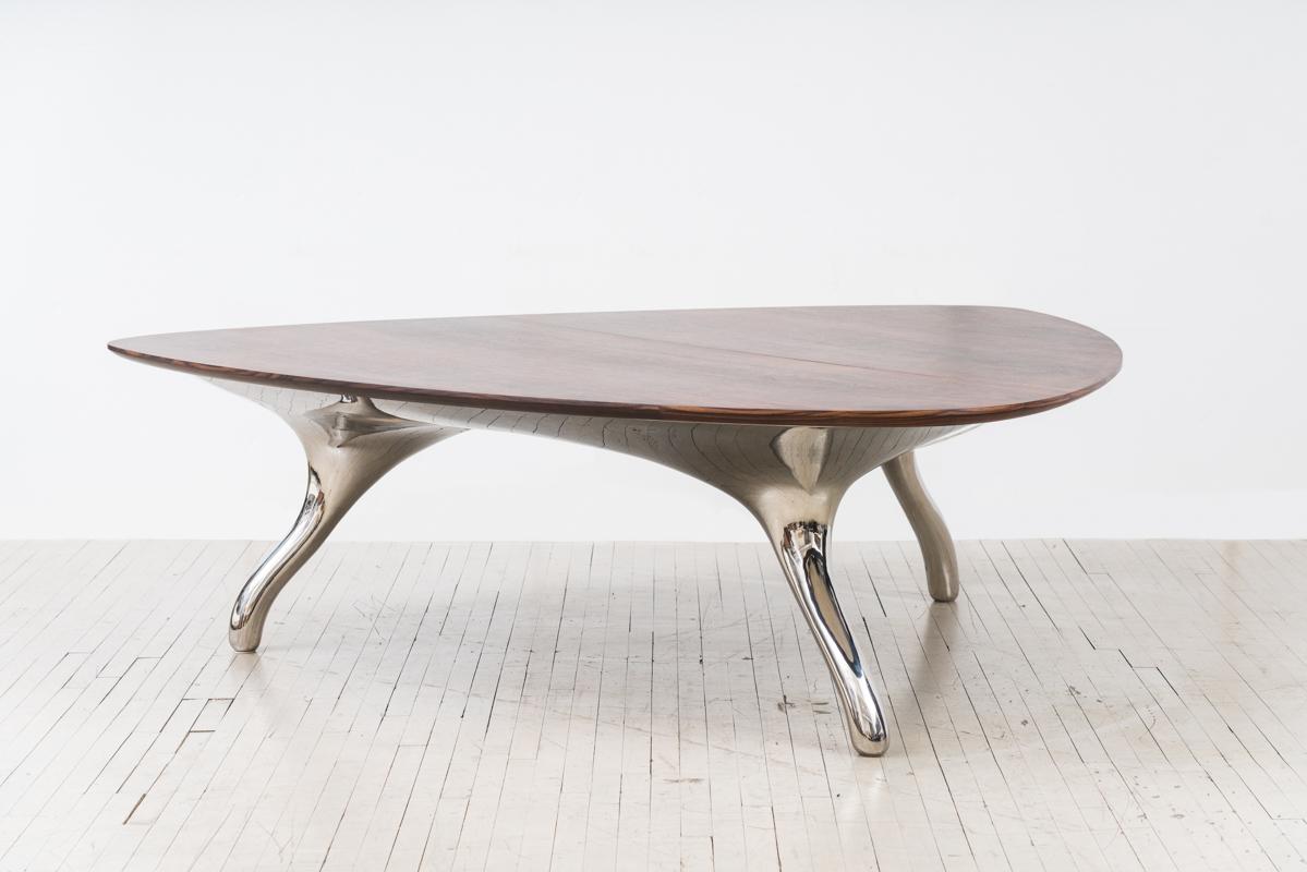 With each of its three sides a generous 93 inches wide, Alex Roskin’s Grand Asymmetric dining table can seat a dinner party of 12. Resting on a sparkling tripod base of mirror-polished stainless steel, the asymmetric three-sided table top is an