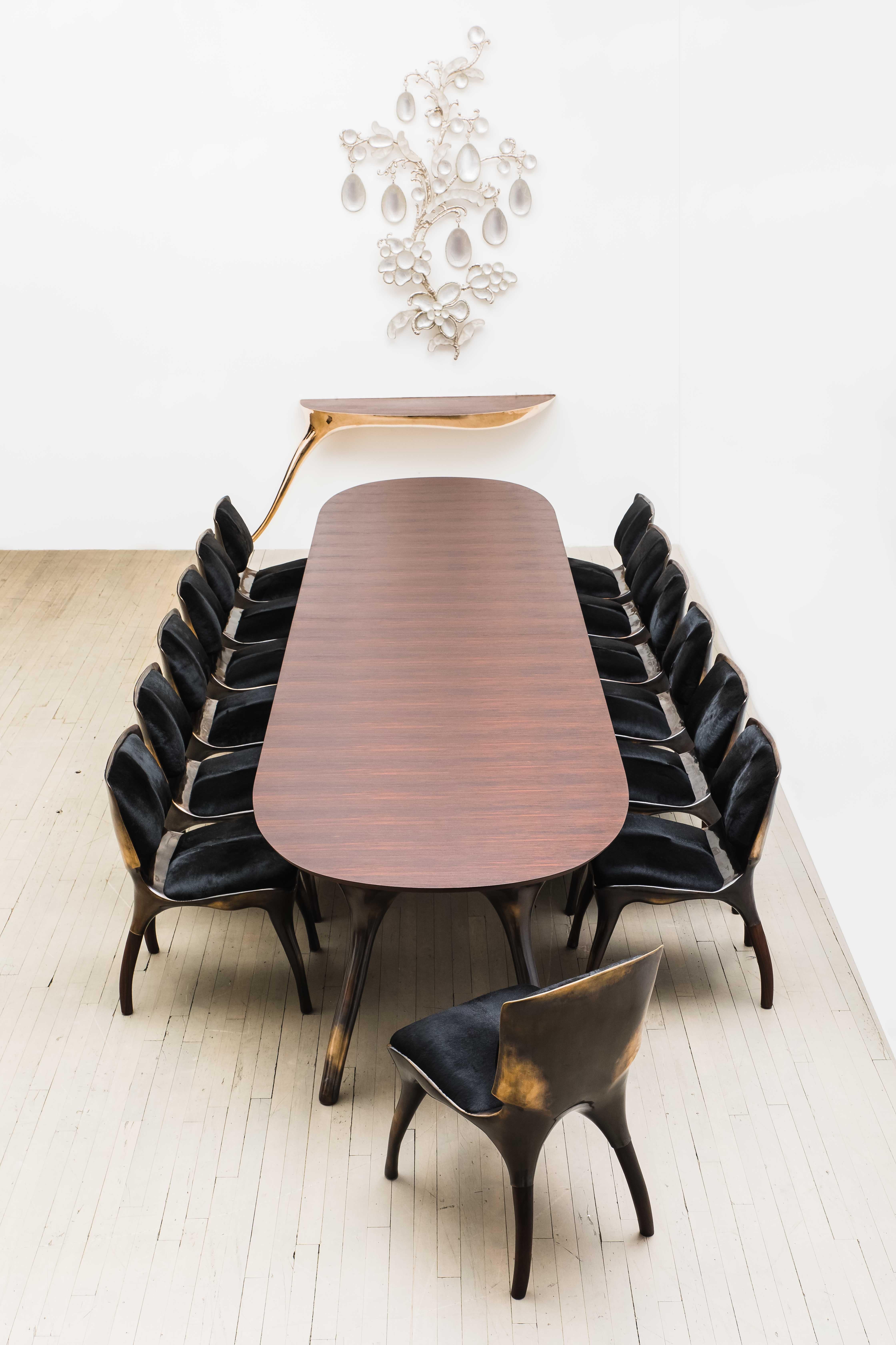 Alex Roskin’s Monumental bronze and rosewood dining table runs an impressive 14 feet, with the ability to seat between 12 to 14 people. The table’s base follows Roskin’s penchant for muscular forms, bowed and sinuous. The base form is first sculpted