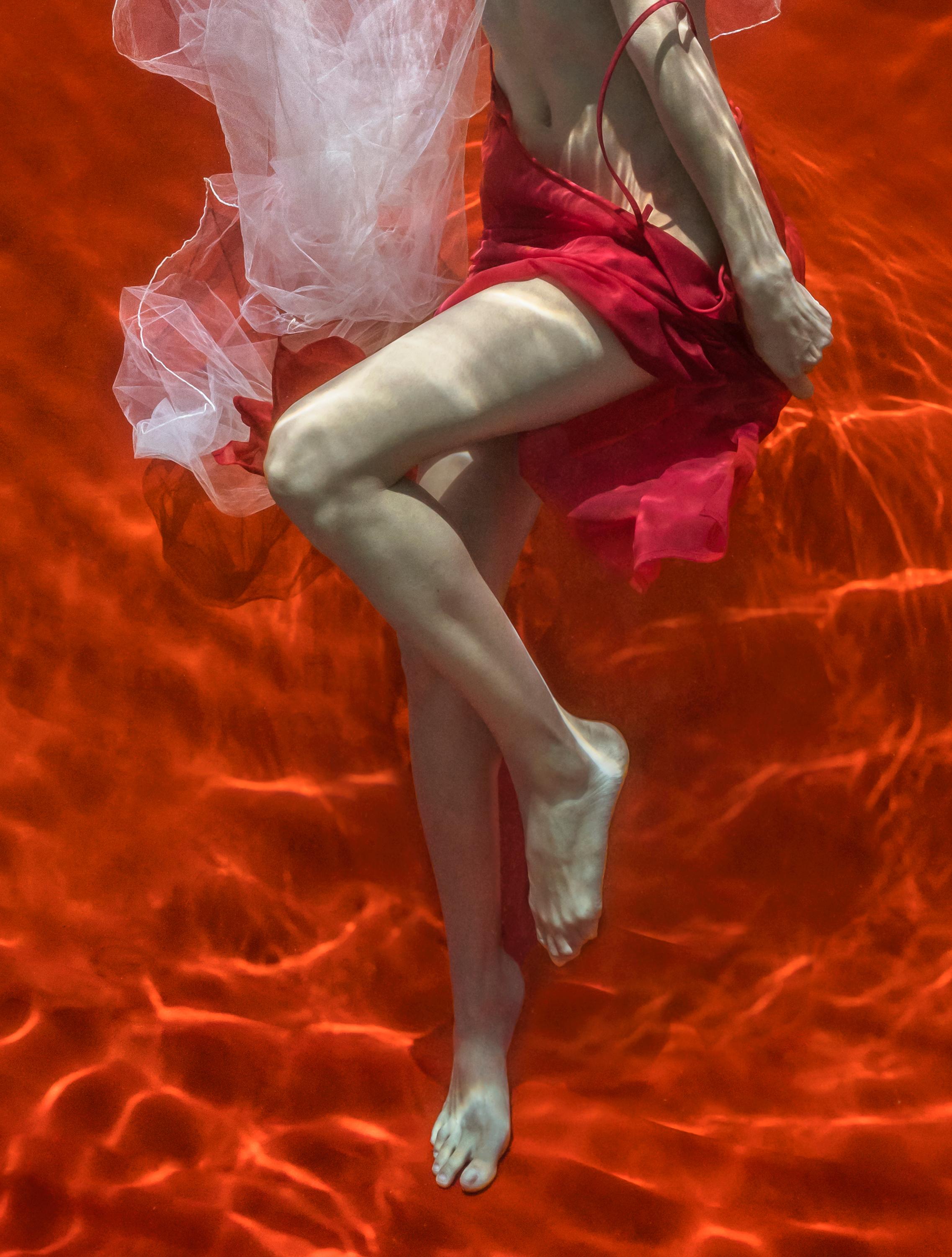 An underwater photograph of a topless young woman with white tulle scarf taking off her red skirt on bright red background. 

Original digital print on archival paper signed by the artist.
Limited edition of 24 
Paper size: 36x27