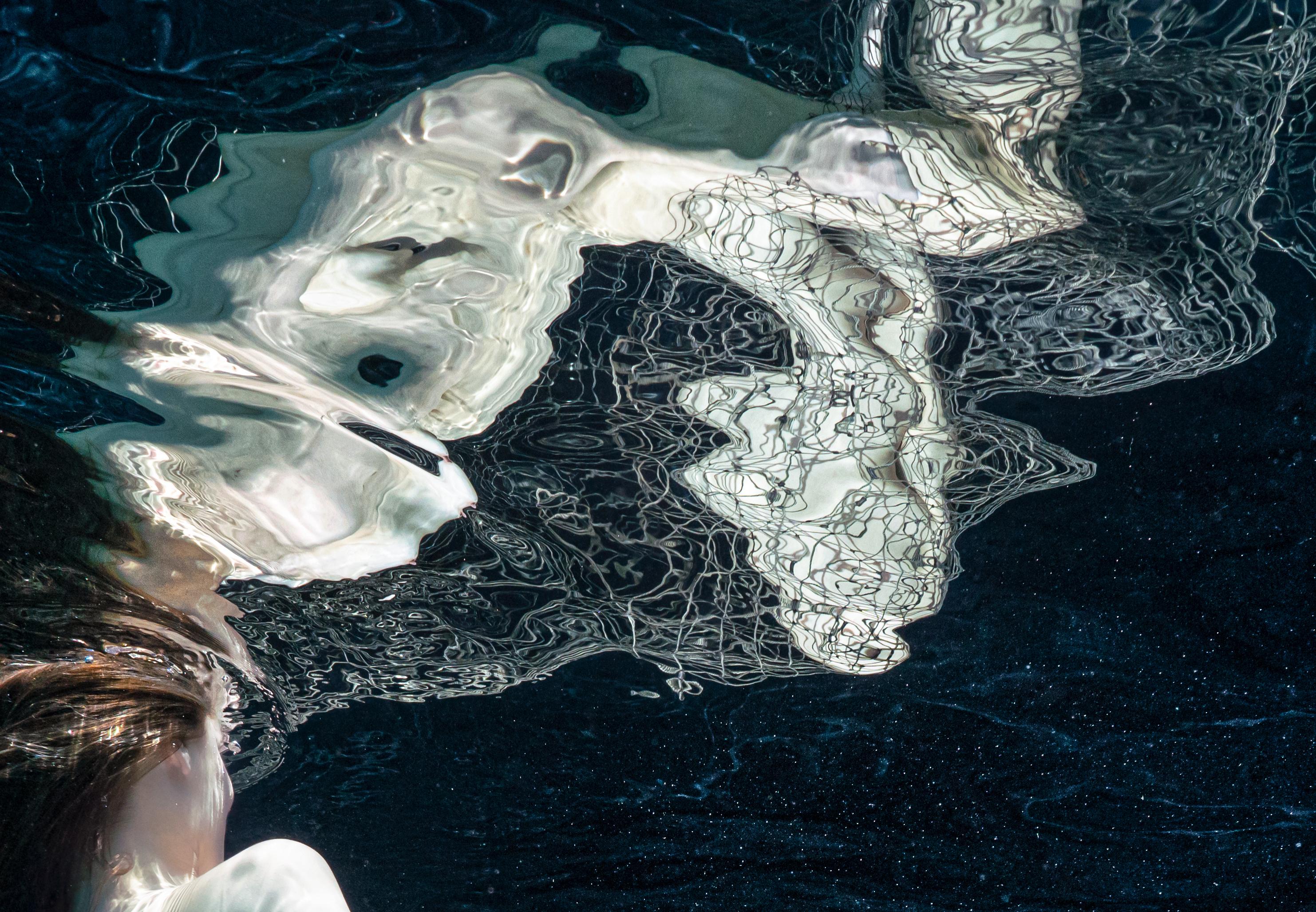 Photographie sous-marine presque monochrome d'une jeune femme nue enveloppée dans un filet de pêche.

Tirage pigmentaire original de qualité galerie sur papier d'archives signé par l'artiste, accompagné d'un certificat d'authenticité.
Edition
