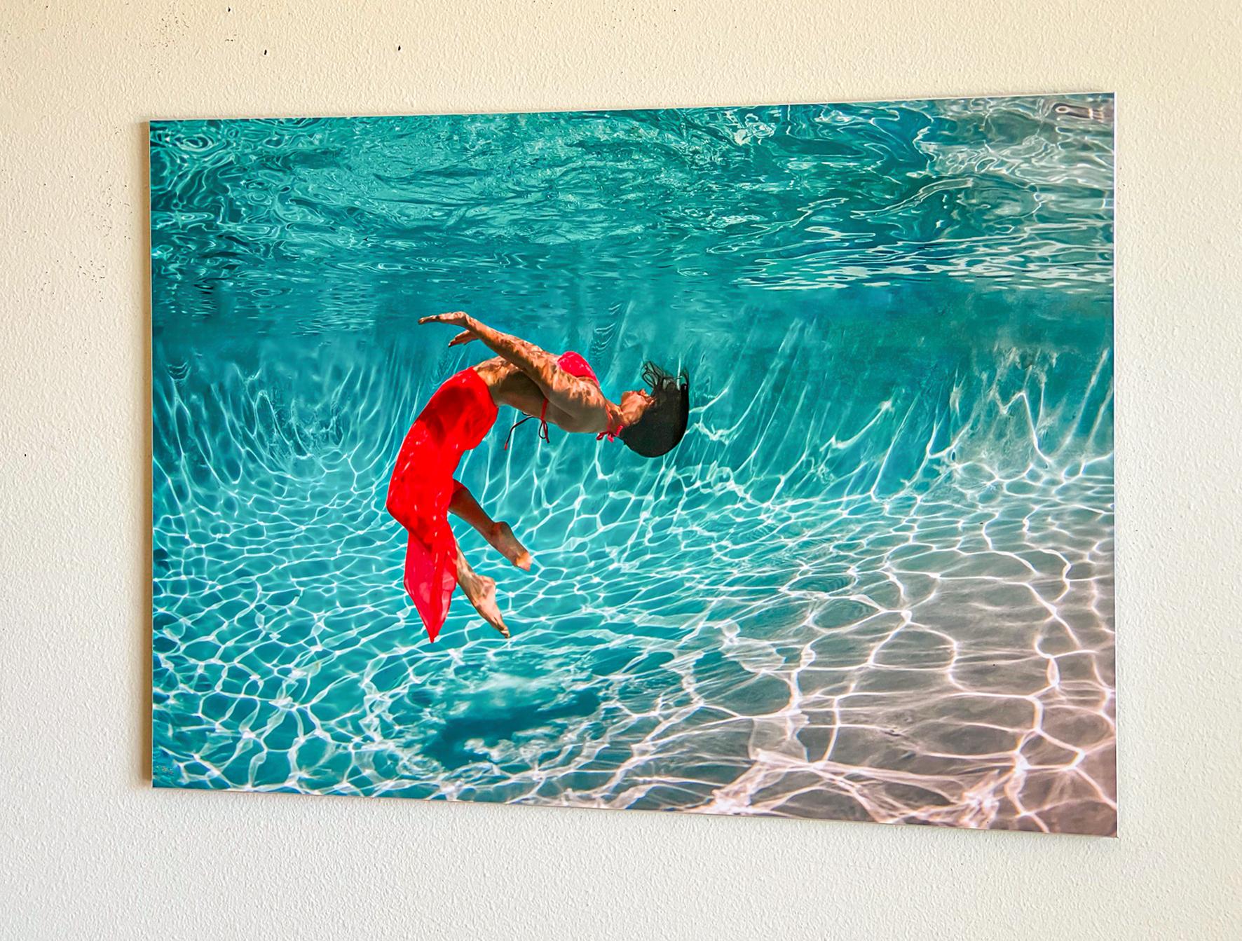 Unterwasserfoto einer jungen Frau in rotem Kleid, die in einem Pool unter Wasser tanzt. Ein sehr helles Foto mit viel Sonne und Positivität.

Modell: die russische Tänzerin Olga Sokolova.  Sehen Sie sich ihren Auftritt 