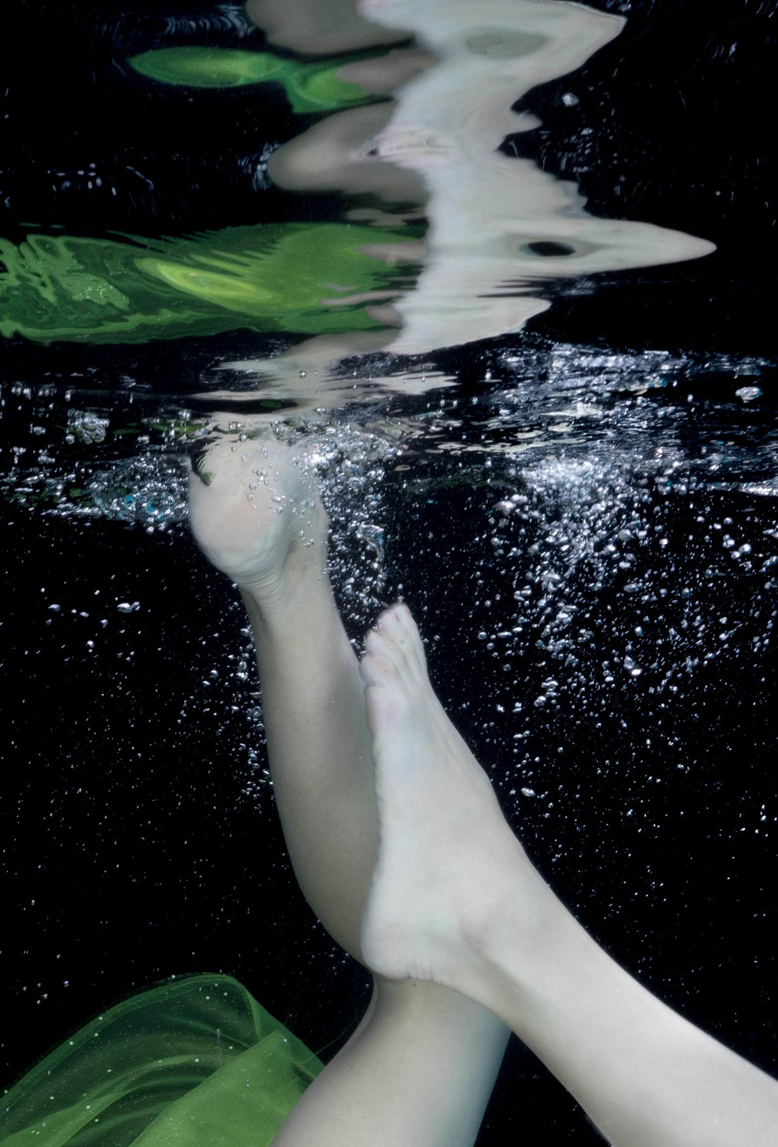 Unterwasser Aktfotografie einer schönen jungen Frau beim Tauchen auf tiefschwarzem Hintergrund. Ein leuchtend grüner Schal bedeckt ihre Brüste und lässt ihre perfekt geformten Pobacken frei. 

Original-Pigmentdruck in Galeriequalität, vom Künstler