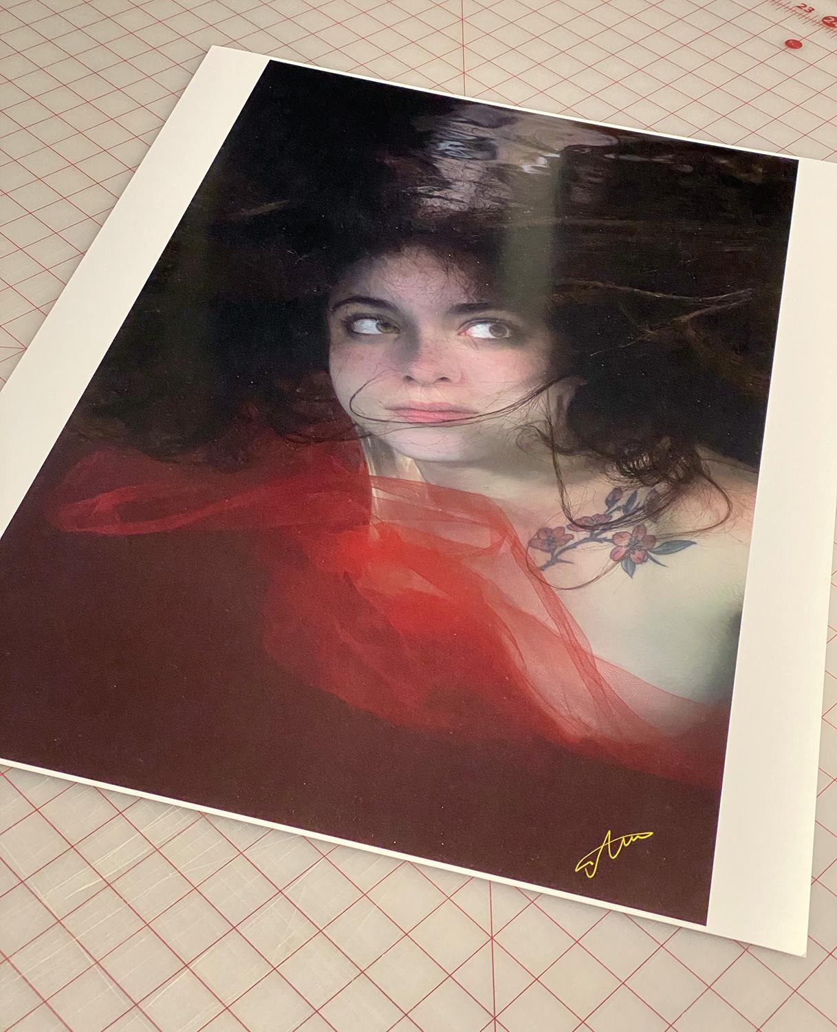 An underwater photograph of a beautiful topless model wrapped in red tulle. 

Original gallery quality archival pigment print signed by the artist.
Limited edition of 12
Paper size: 36