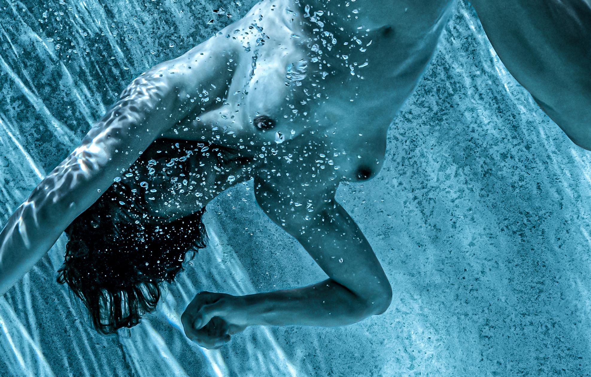 Eine schöne  und anspruchsvolles Unterwasserfoto einer jungen nackten Frau im Schwimmbad.  Es handelt sich um eine Schwarz-Weiß-Fotografie mit einer aquatischen Tönung, die an Schwarz-Weiß erinnert. Dies ist das dritte Foto aus der